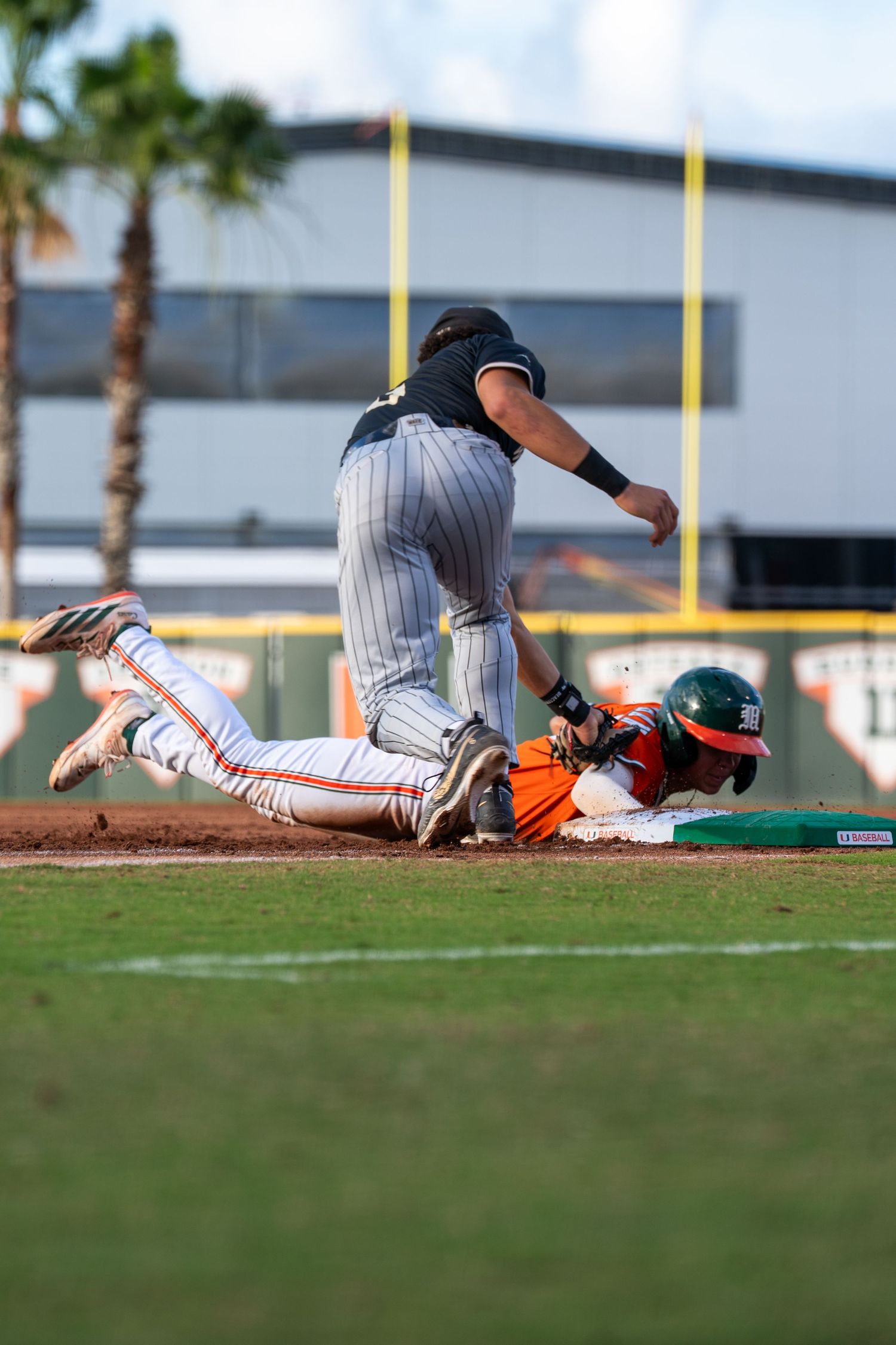 Baseball player sliding into base as fielder attempts a tag during an intense game.