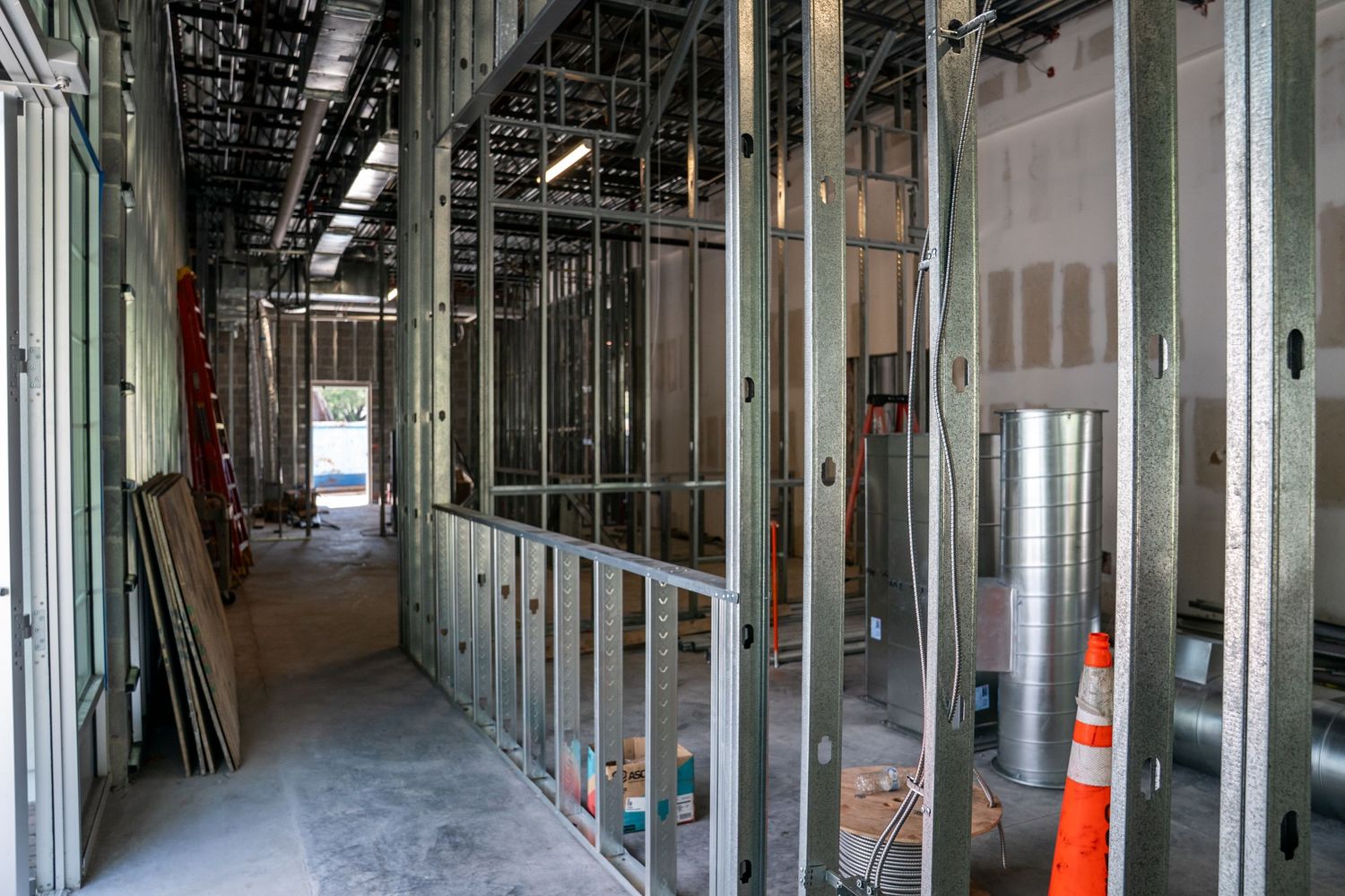 Construction site hallway with metal studs and exposed ceiling showing building progress.