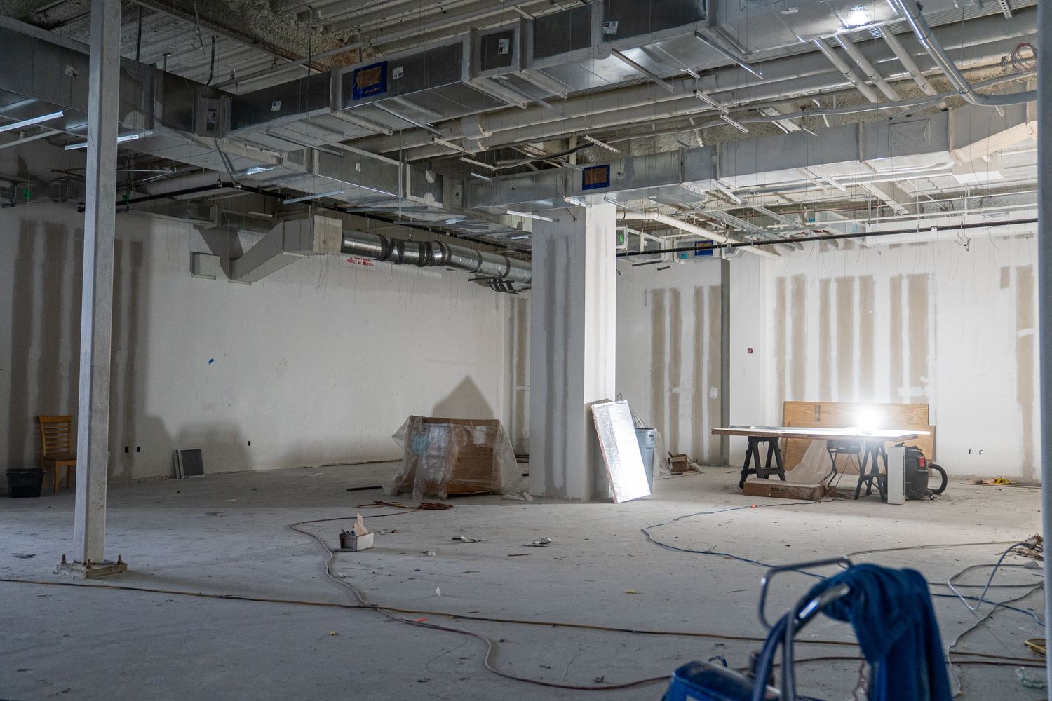 Unfinished commercial space with white walls and exposed ductwork in ceiling.
