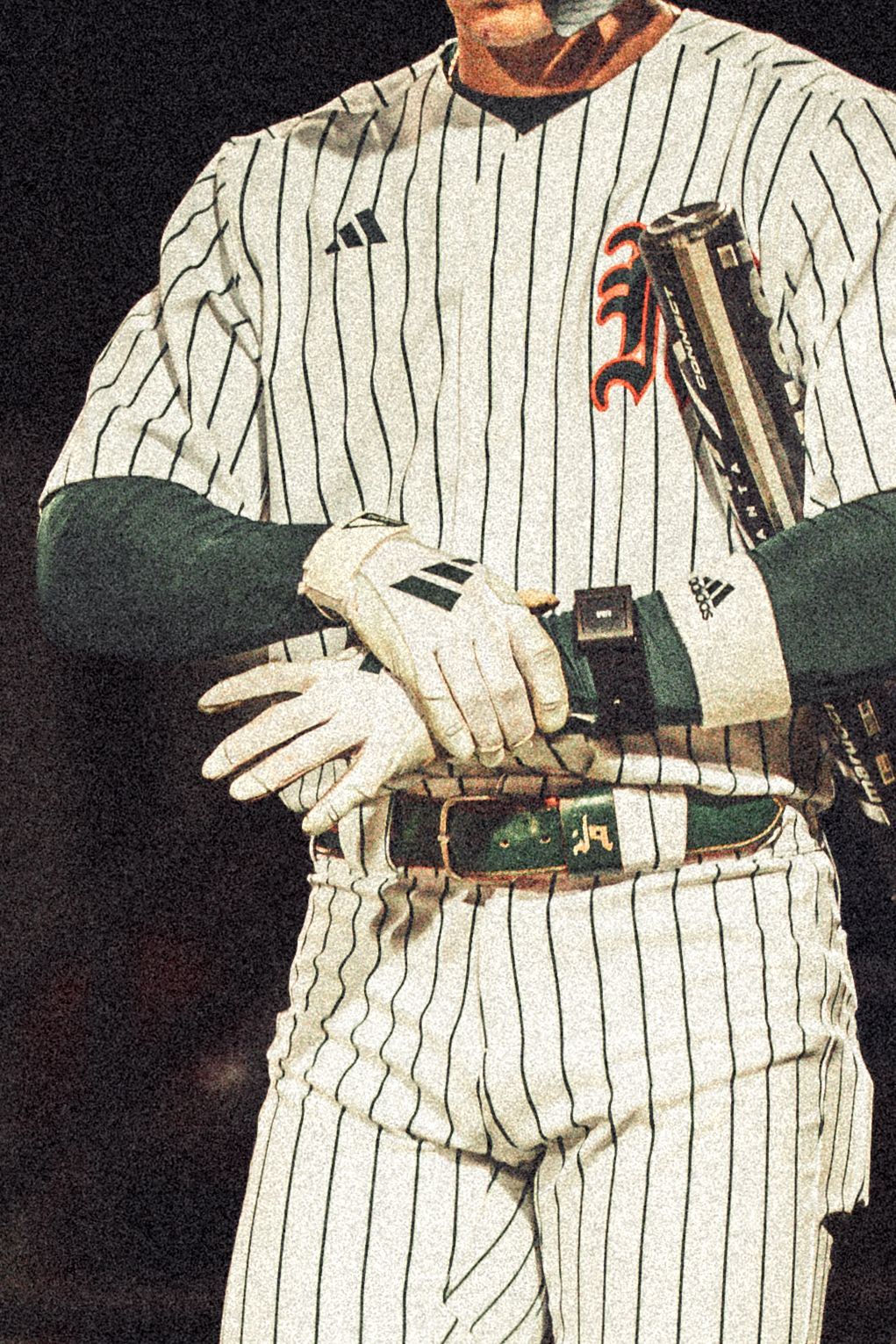 Baseball player in white pinstripe Adidas uniform holding bat with batting gloves, wearing green undershirt.
