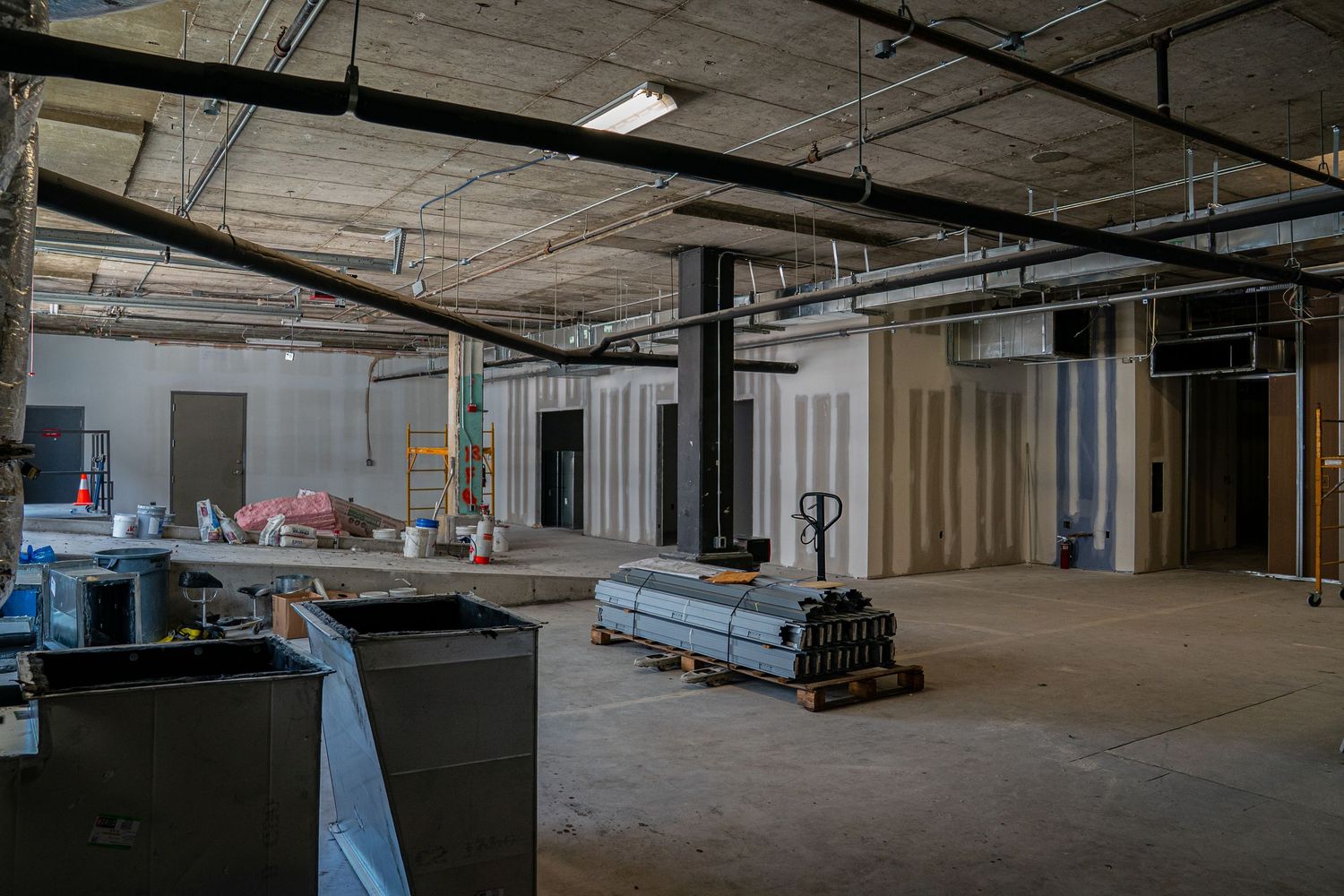 Interior view of an empty commercial space under construction with exposed ceiling and concrete floors.