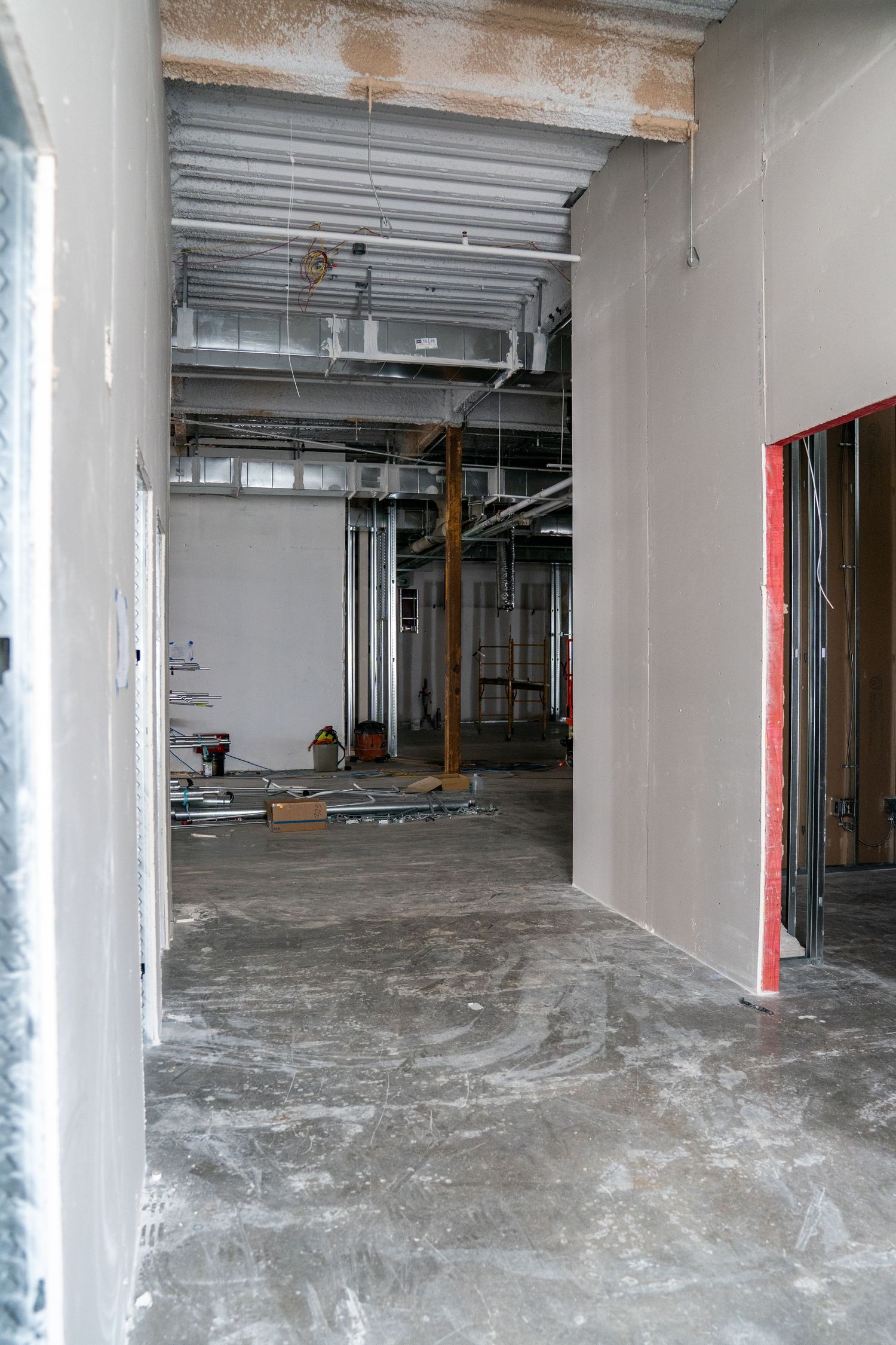 White-walled commercial space under construction with exposed concrete floors and support columns.
