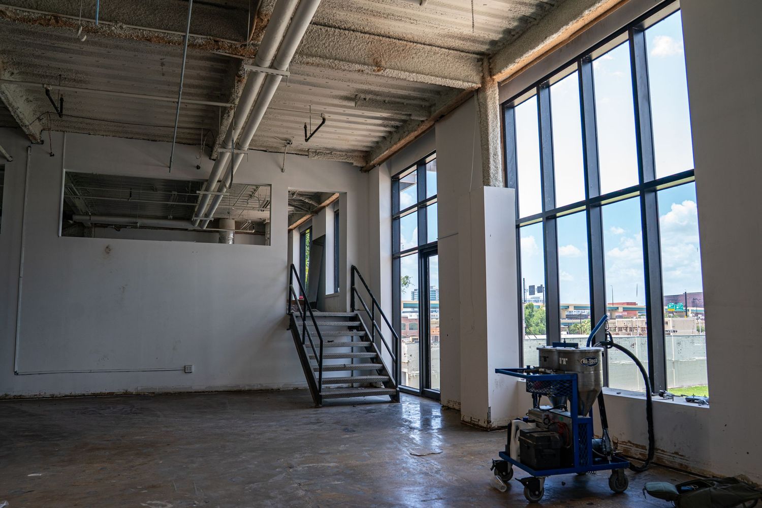 Modern industrial space with floor-to-ceiling windows providing natural illumination.