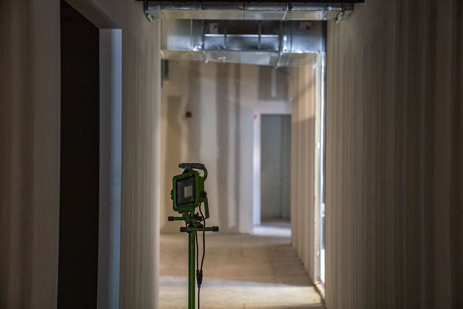Industrial corridor with white walls and exposed ductwork showing construction progress.