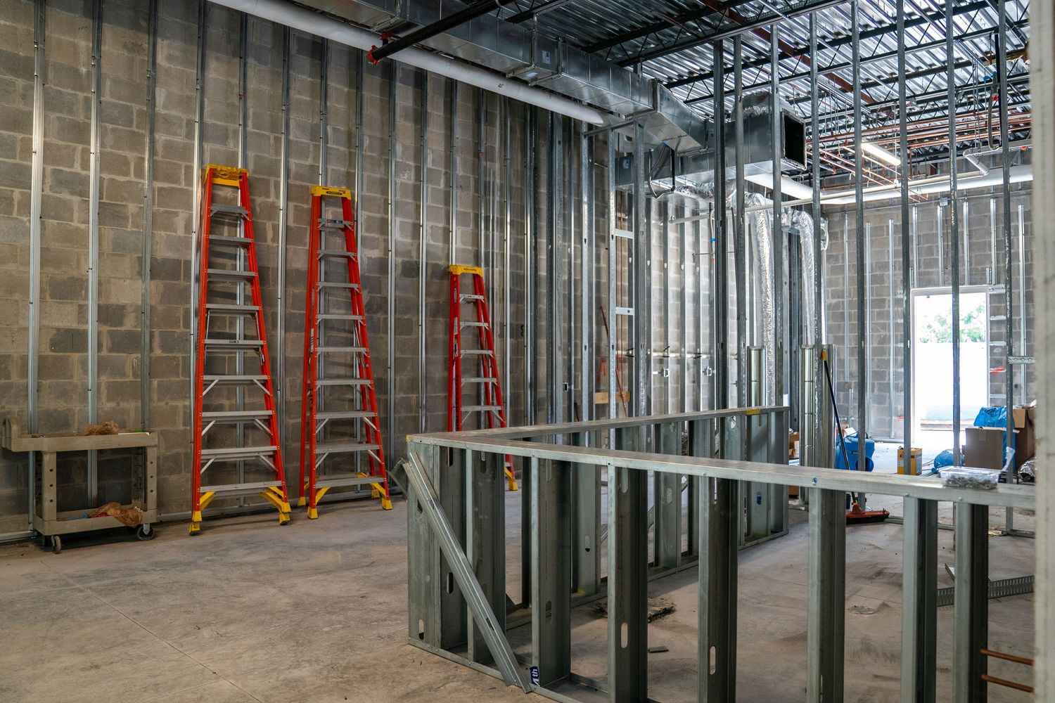 Wide view of commercial construction site with metal studs and concrete block walls.