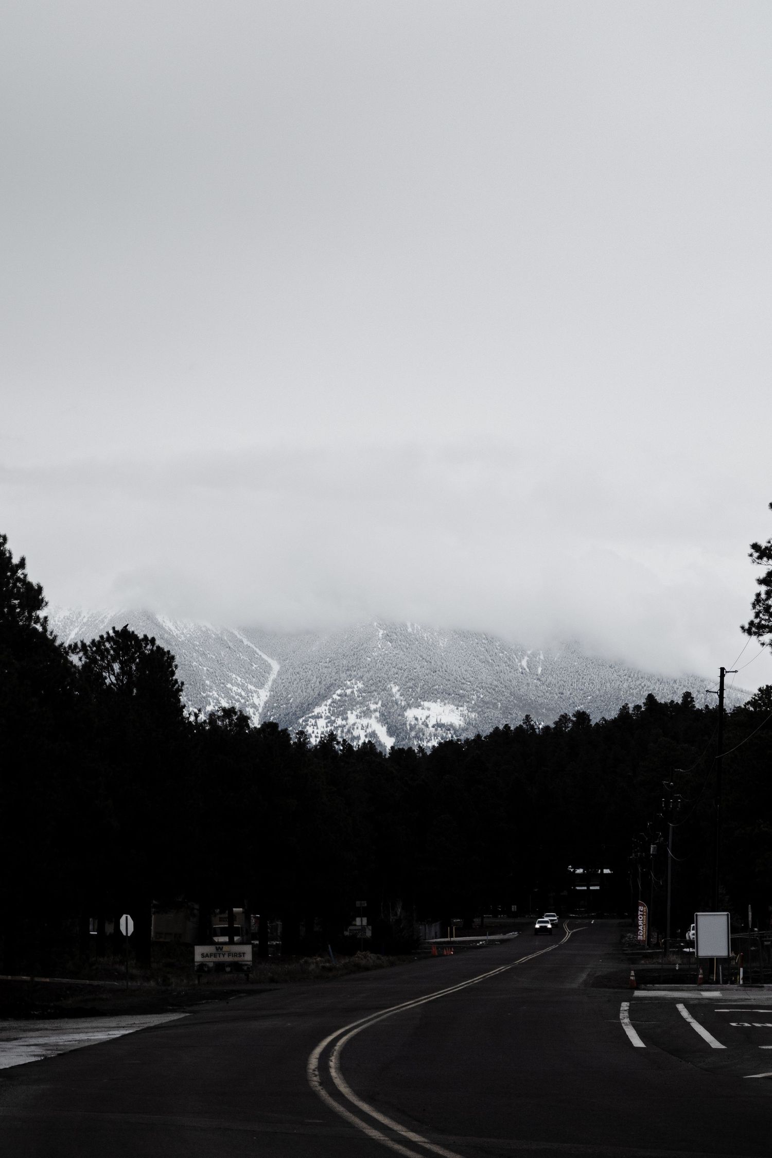 Winding road leading toward snow-capped mountains under overcast winter sky.