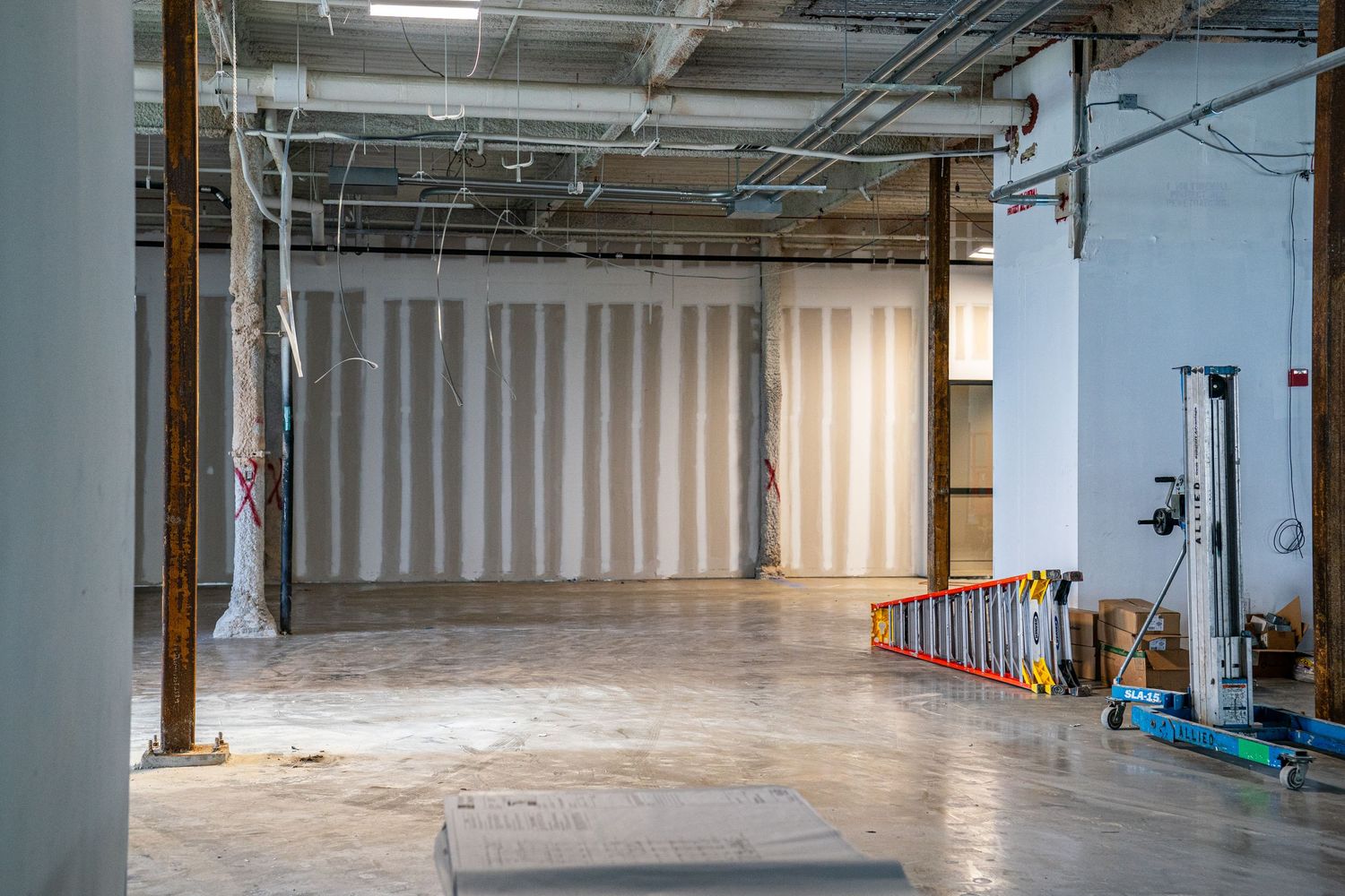 Large empty industrial warehouse space with exposed ceiling and concrete floors.