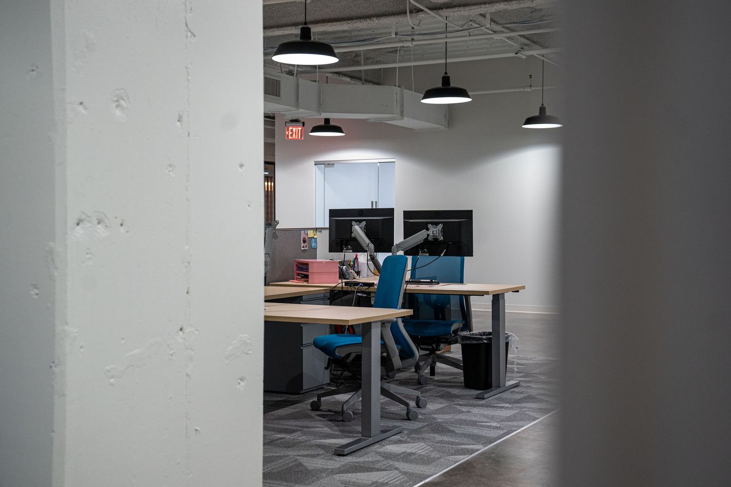 Unfinished commercial interior with suspended lighting and exposed mechanical systems.