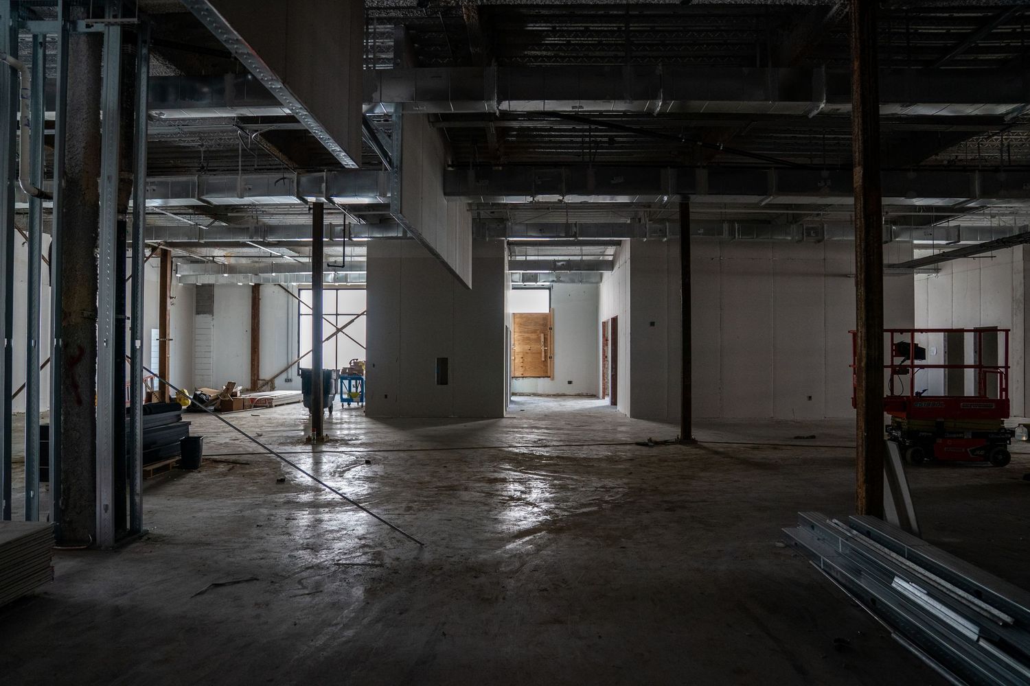 Long view of commercial space under construction showing exposed ceiling and concrete floors.