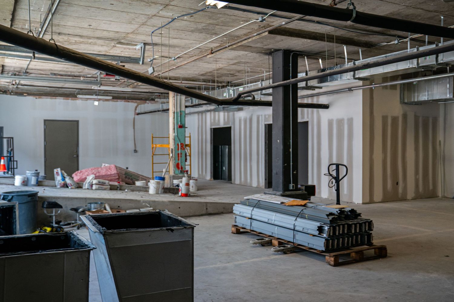 Raw commercial space with construction materials and mechanical systems visible.