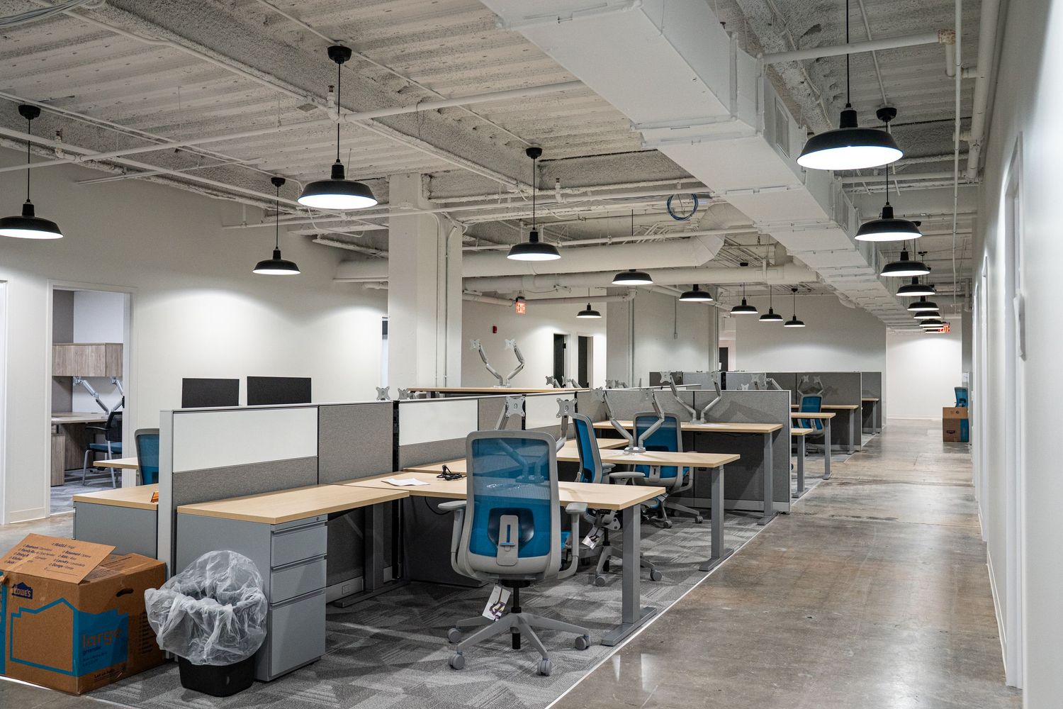 Wide angle view of modern office interior with suspended lighting and collaborative workspace design.