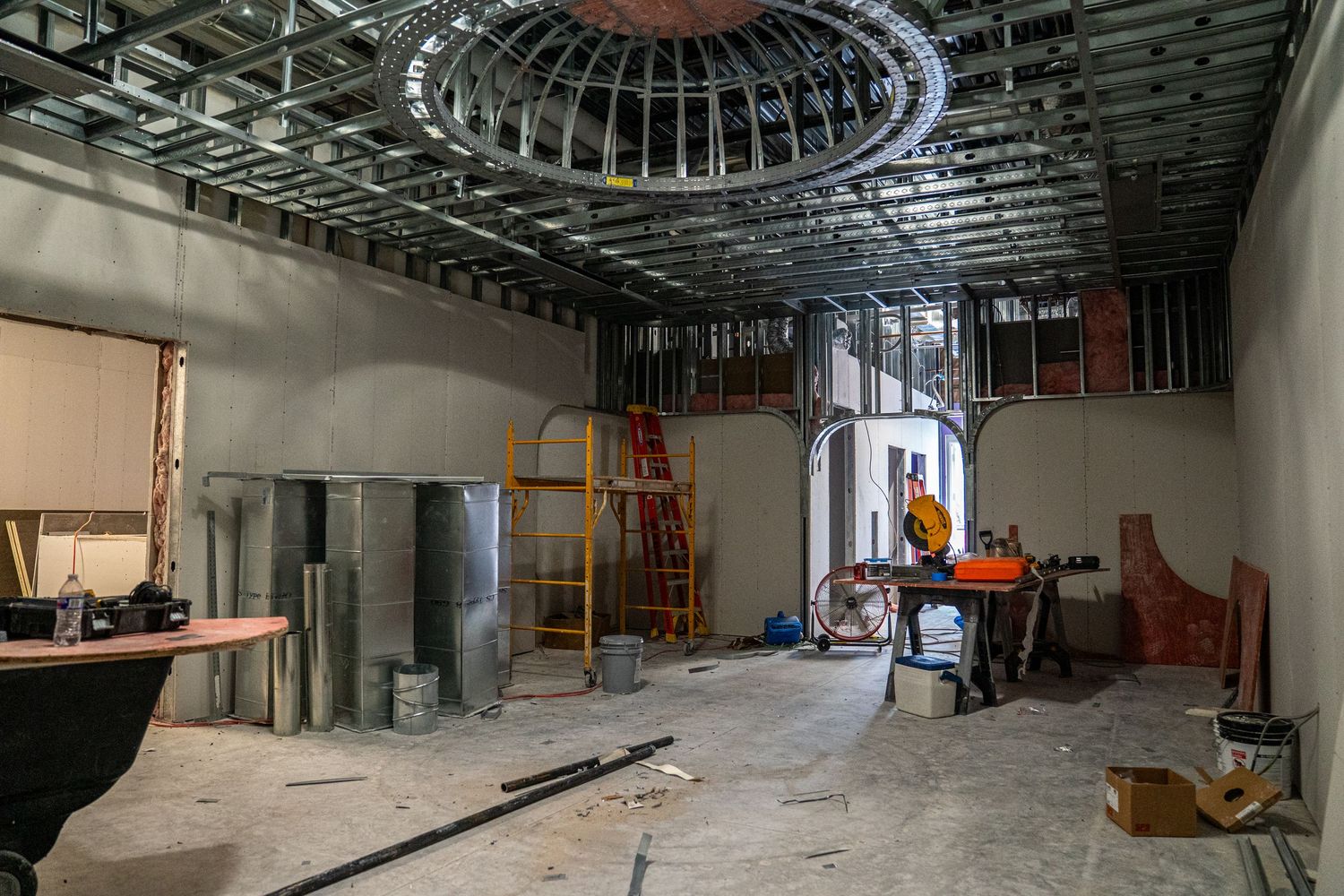 Unfinished commercial space features dramatic circular ceiling detail and construction equipment.