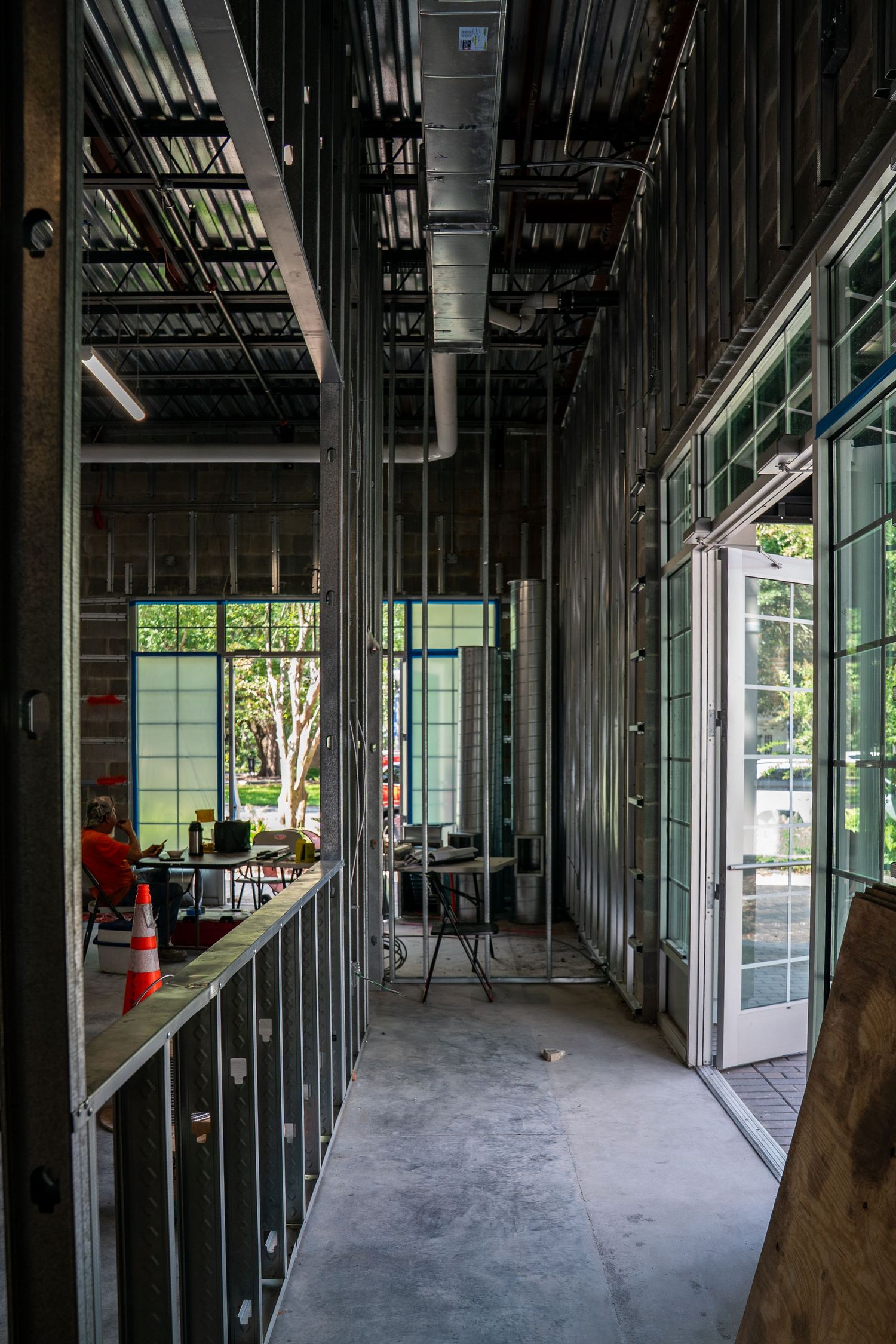 Long corridor view of commercial space under construction with glass windows and metal framing.