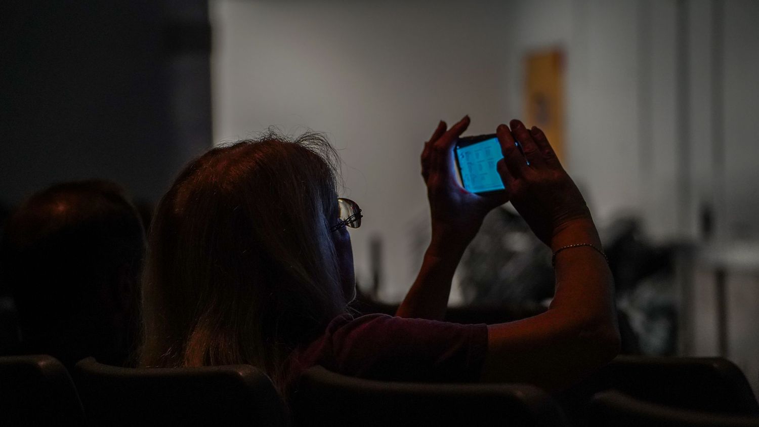 Dark blurred image of people in an indoor setting.