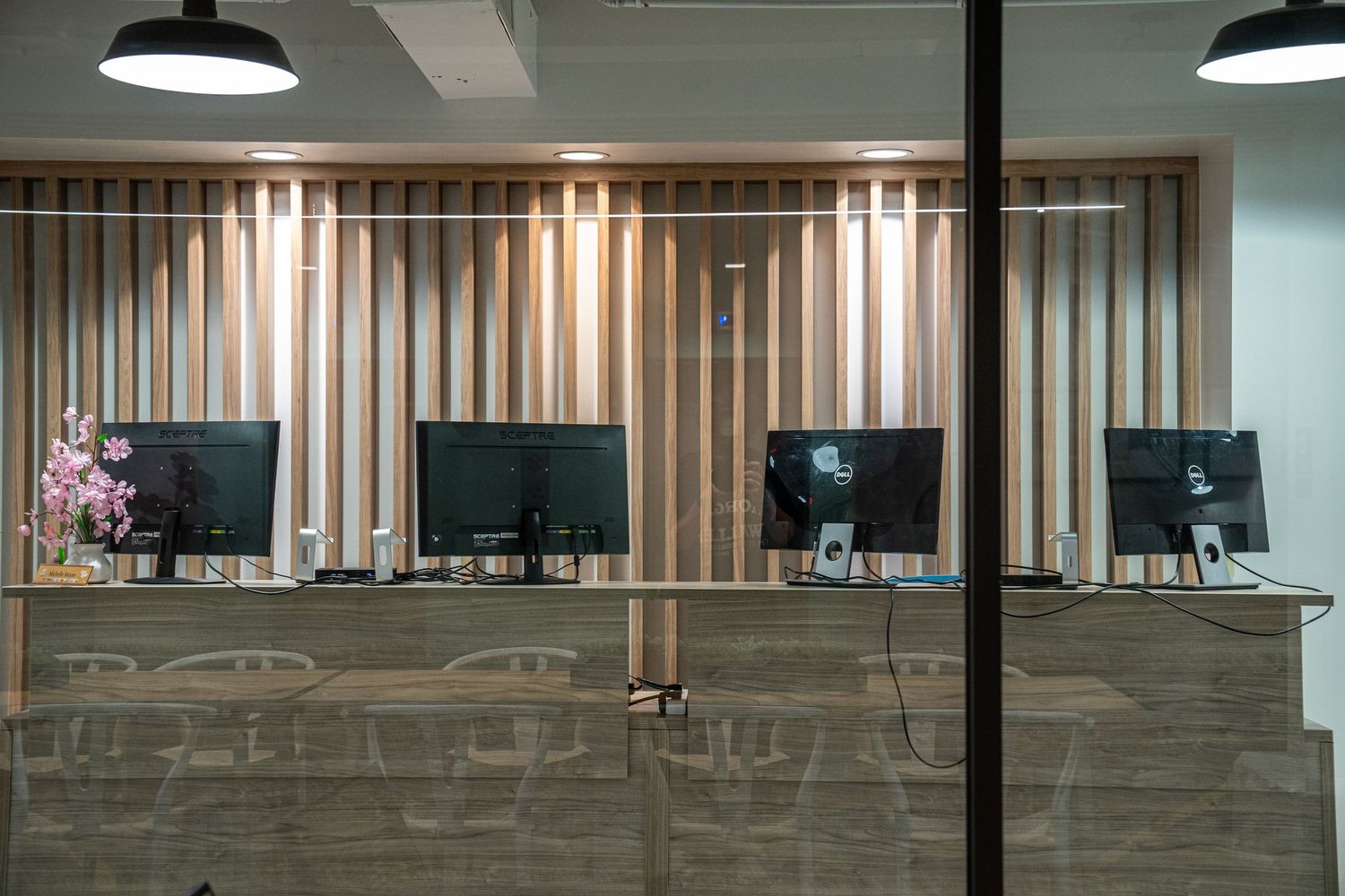 Long office hallway with wooden accent wall panels and recessed lighting creating a warm atmosphere.