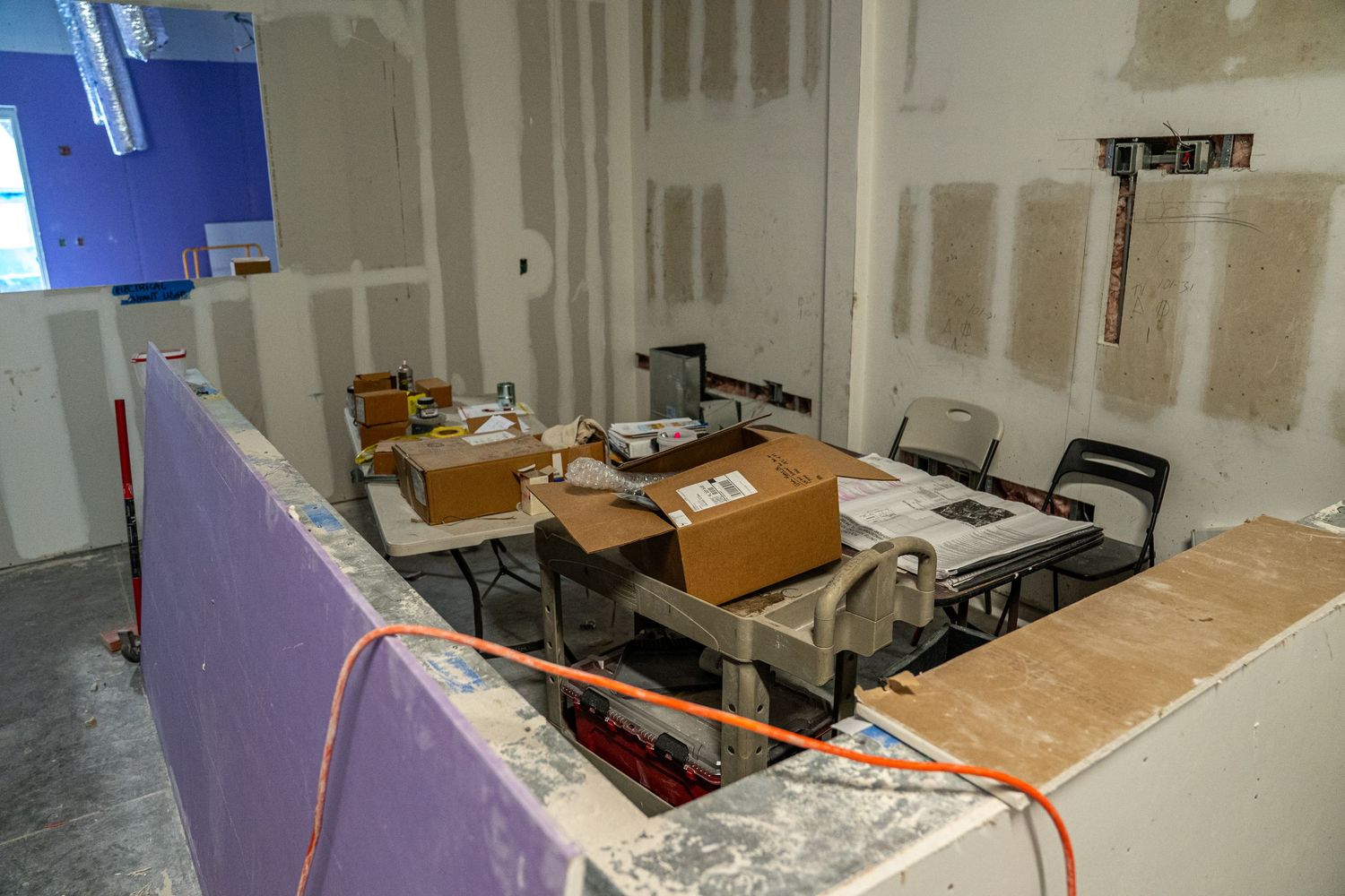 Wide angle view of office space renovation with suspended ceiling framework and drywall.