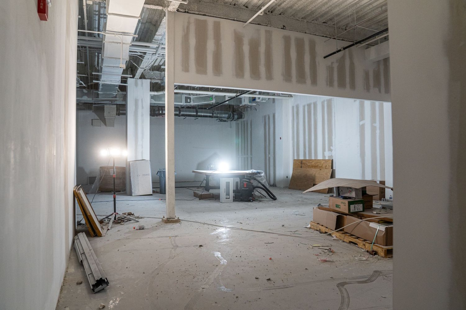 Wide angle view of commercial renovation space with white walls and concrete floor.