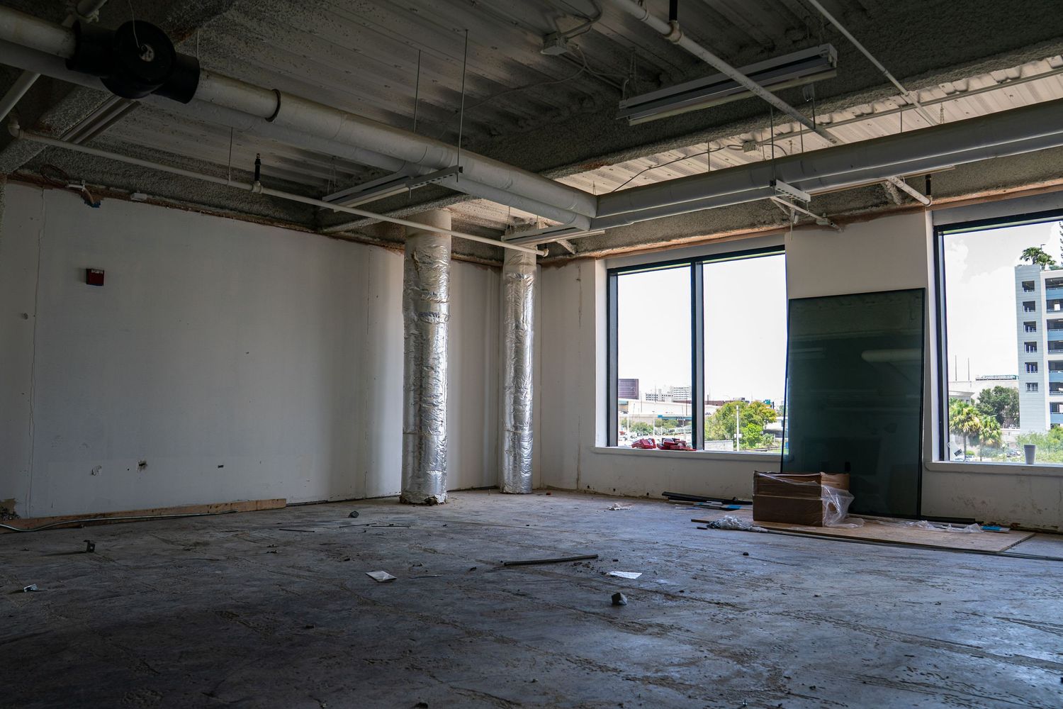 Spacious empty industrial floor with concrete surfaces and natural lighting from large windows.