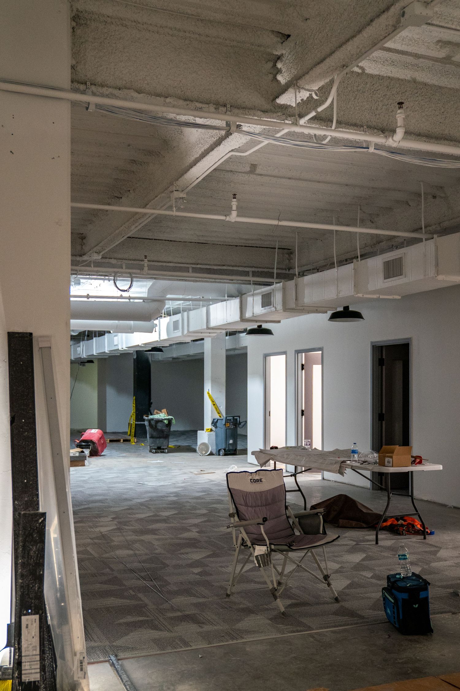 Open office renovation space with scattered furniture and construction materials.
