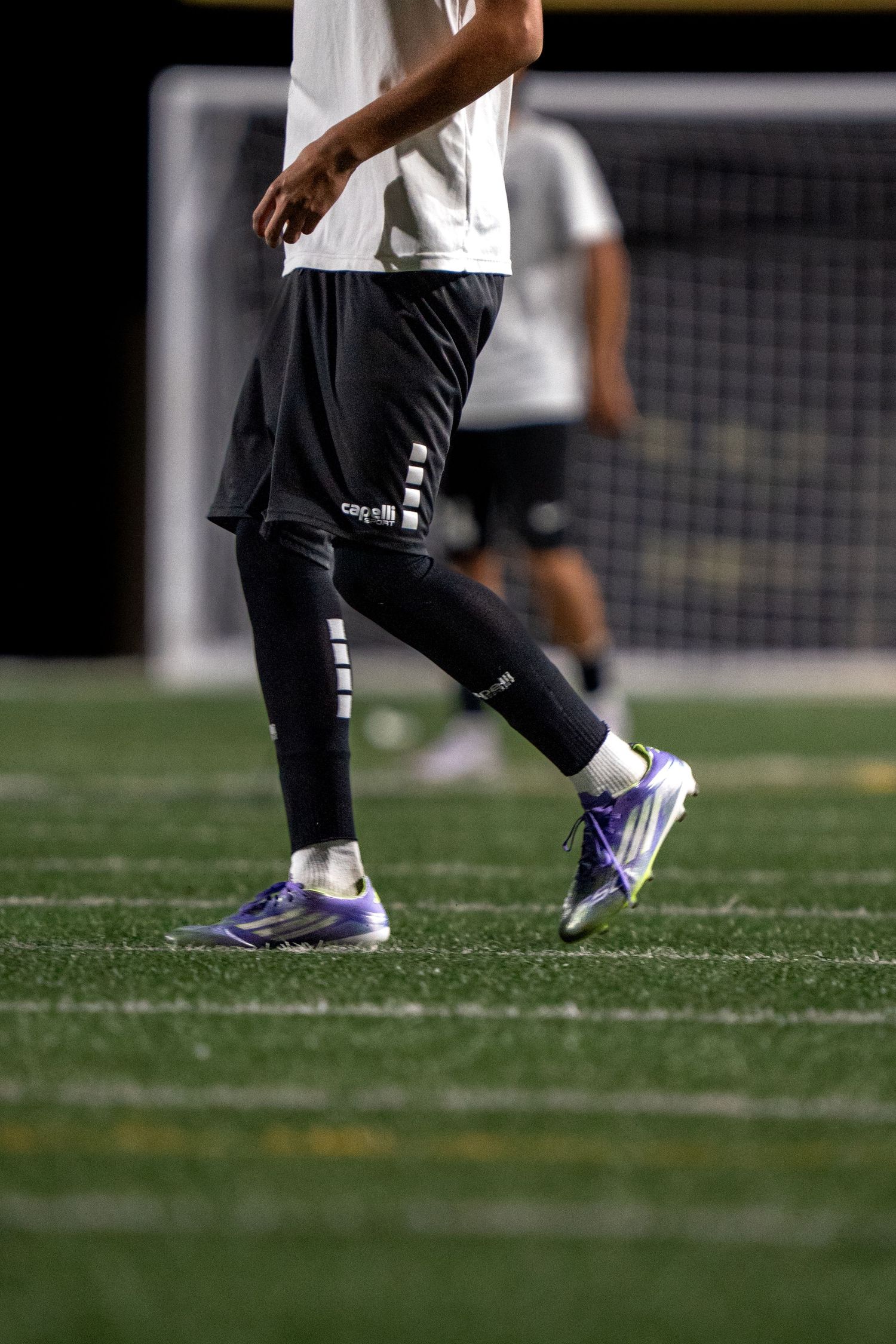 Close-up of athletes' feet walking on green turf field.