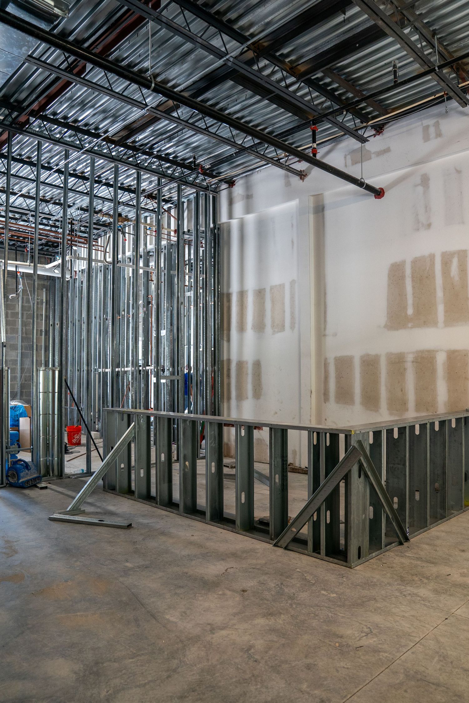 Partially completed interior space showing metal stud framing and unfinished drywall installation.