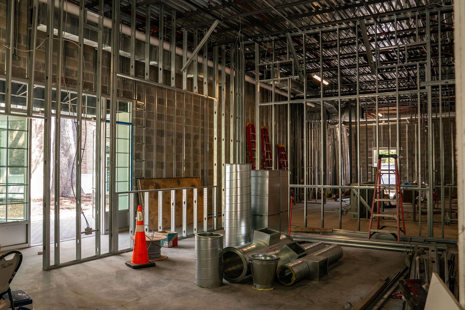 Wide angle view of commercial space renovation showing metal framing and construction progress.