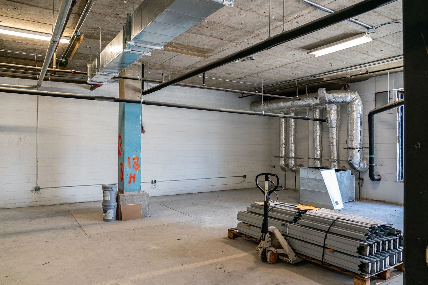 Industrial space under renovation with exposed pipes and electrical conduits.