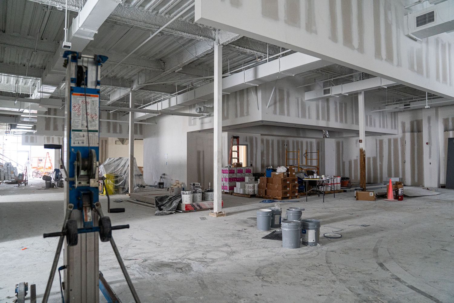 Construction site interior showing open floor plan with scattered equipment and building materials.