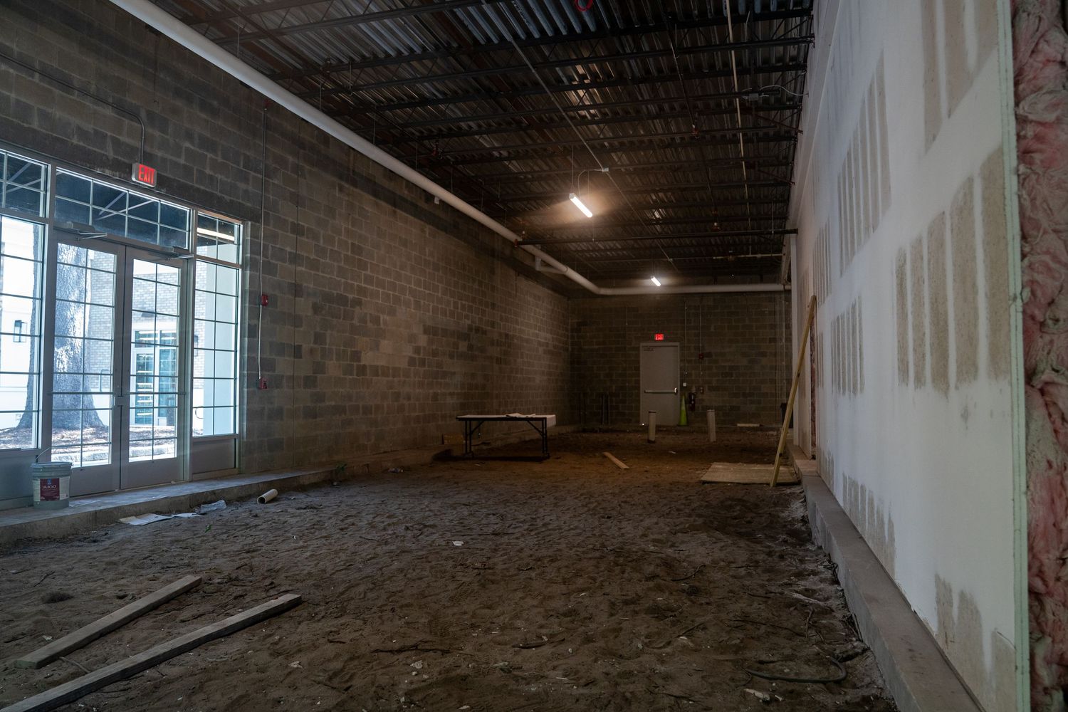 Commercial space under construction with concrete block walls and large storefront windows.