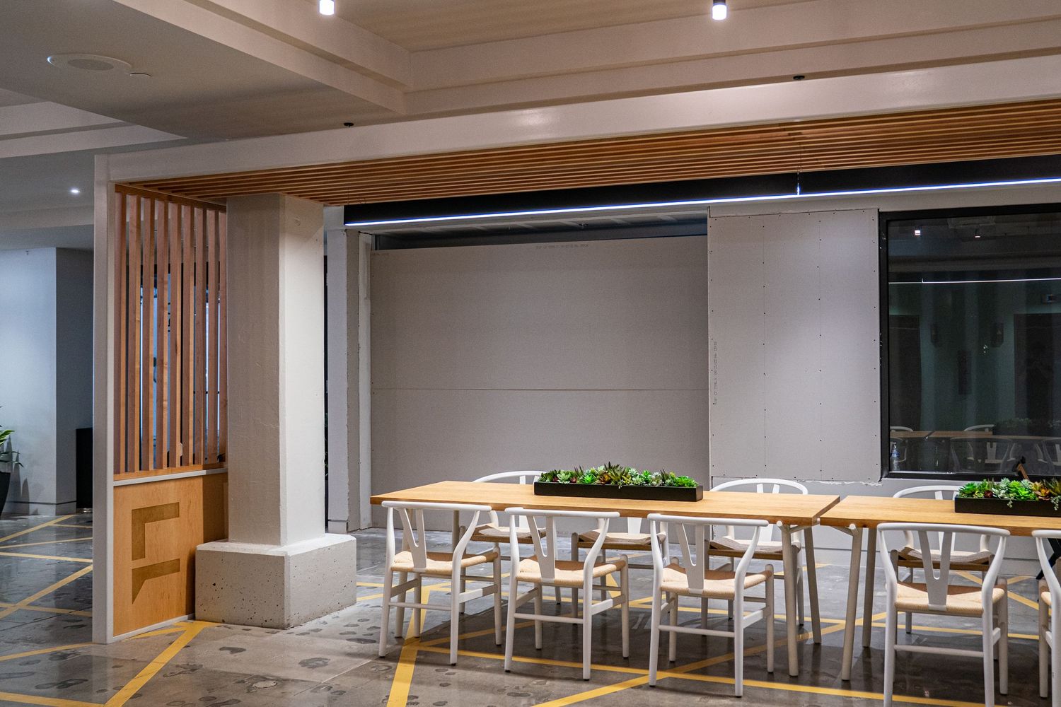 Large empty commercial space with exposed ceiling, concrete floors and modern lighting fixtures.