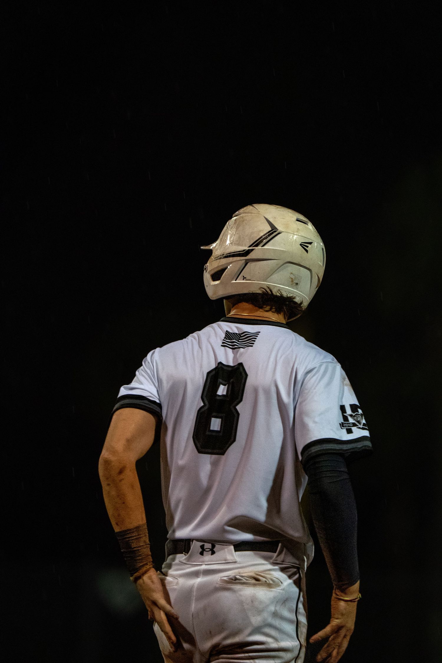 Baseball player in white uniform and cap stands ready in batting position.