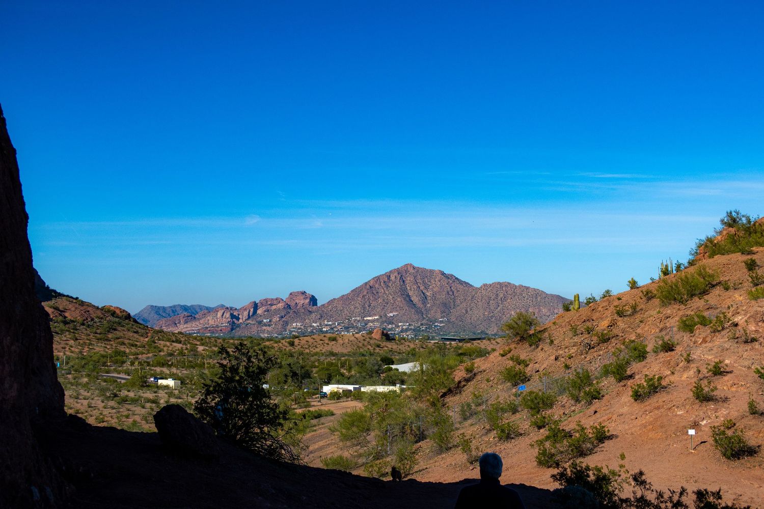 Mountain vista overlooking desert valley with red rocks and clear blue sky.