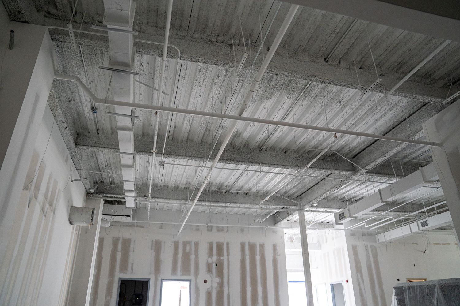 Commercial building interior with exposed ceiling systems and white structural columns.