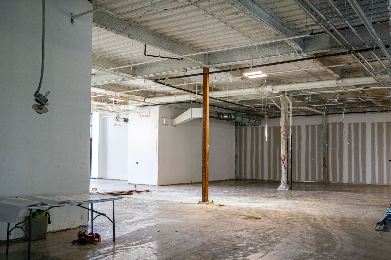 Vacant industrial space showing exposed ceiling infrastructure and support columns.