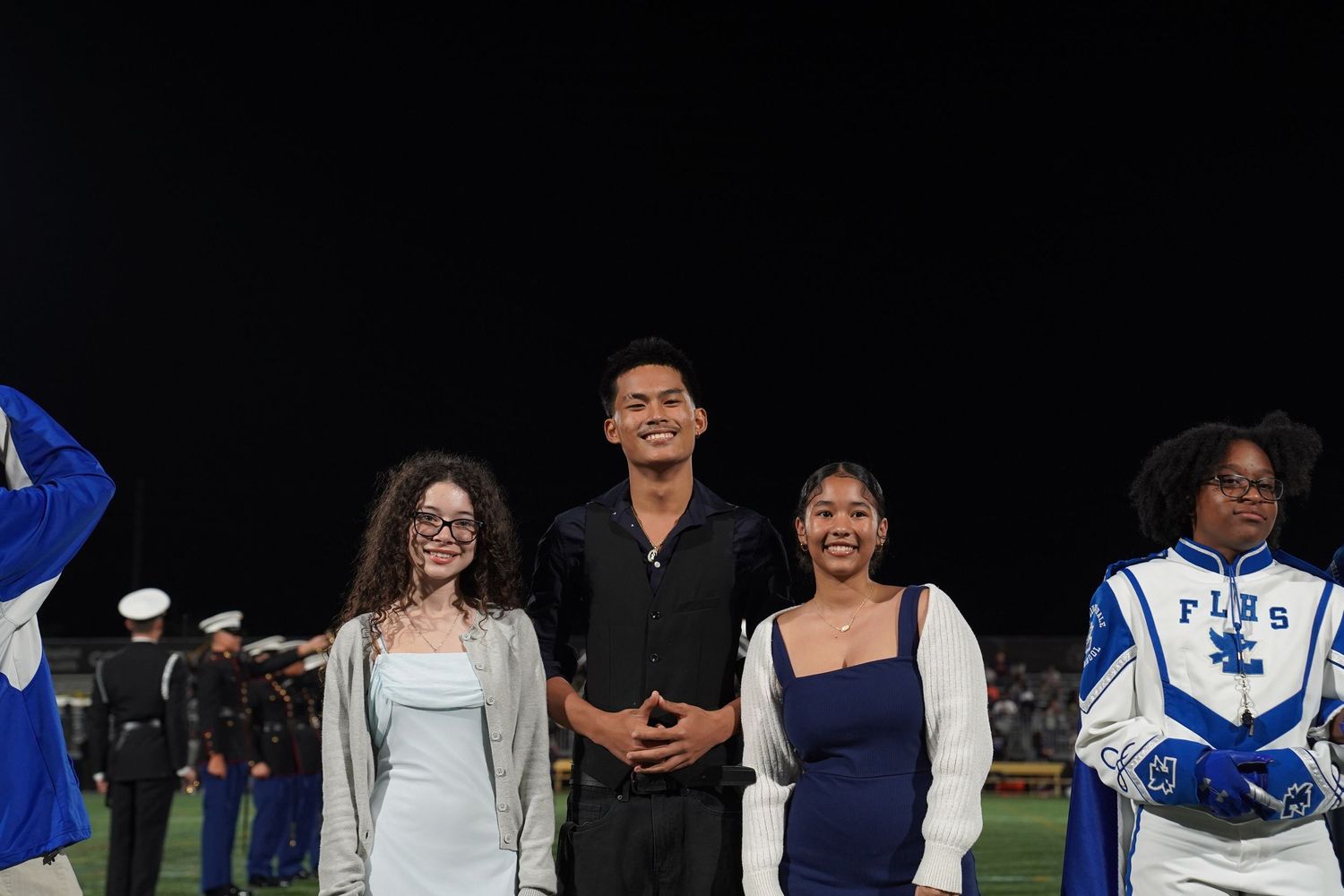 Students lined up for a formal event under stadium lighting at night.