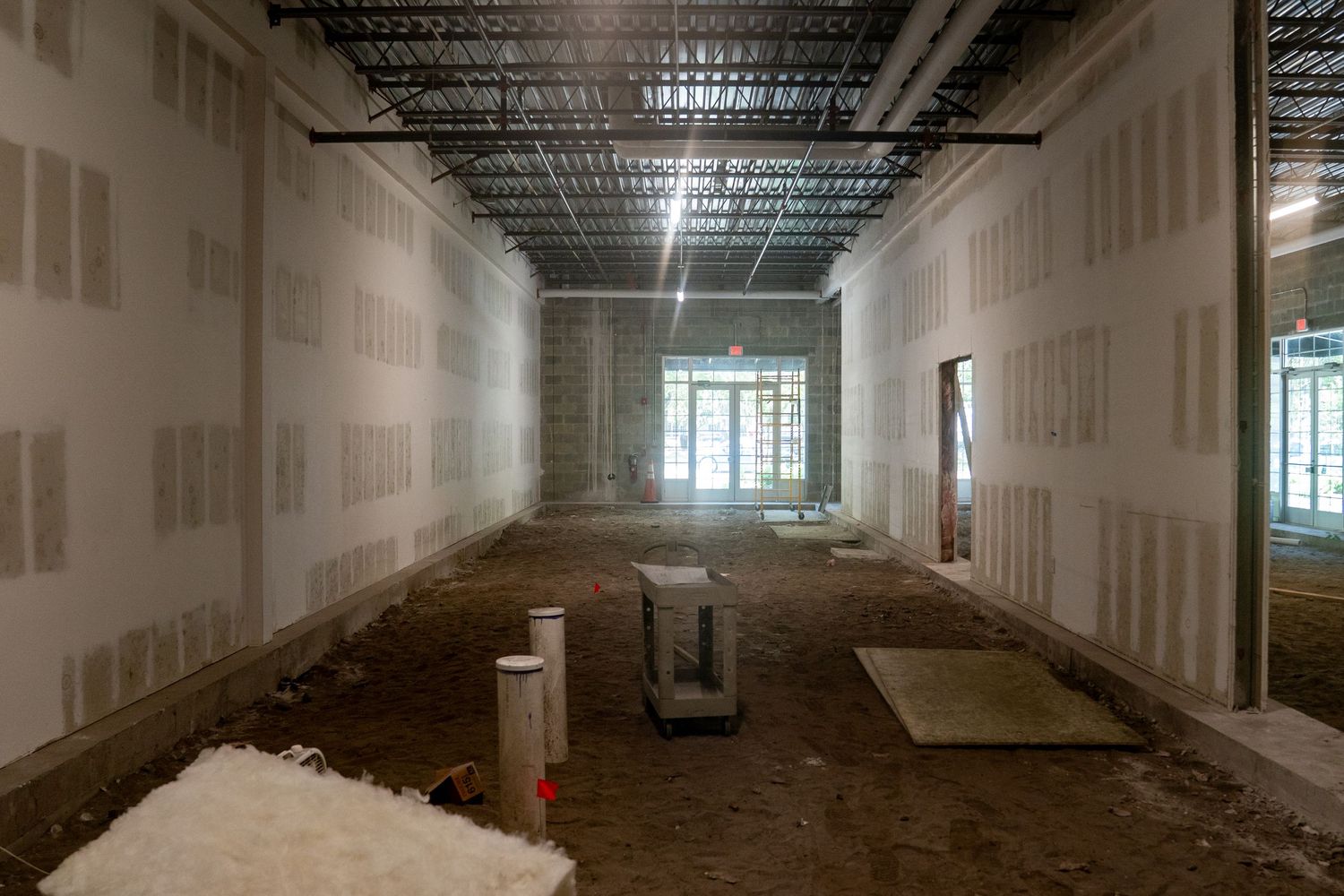 Construction hallway with unfinished drywall and exposed dirt floor.