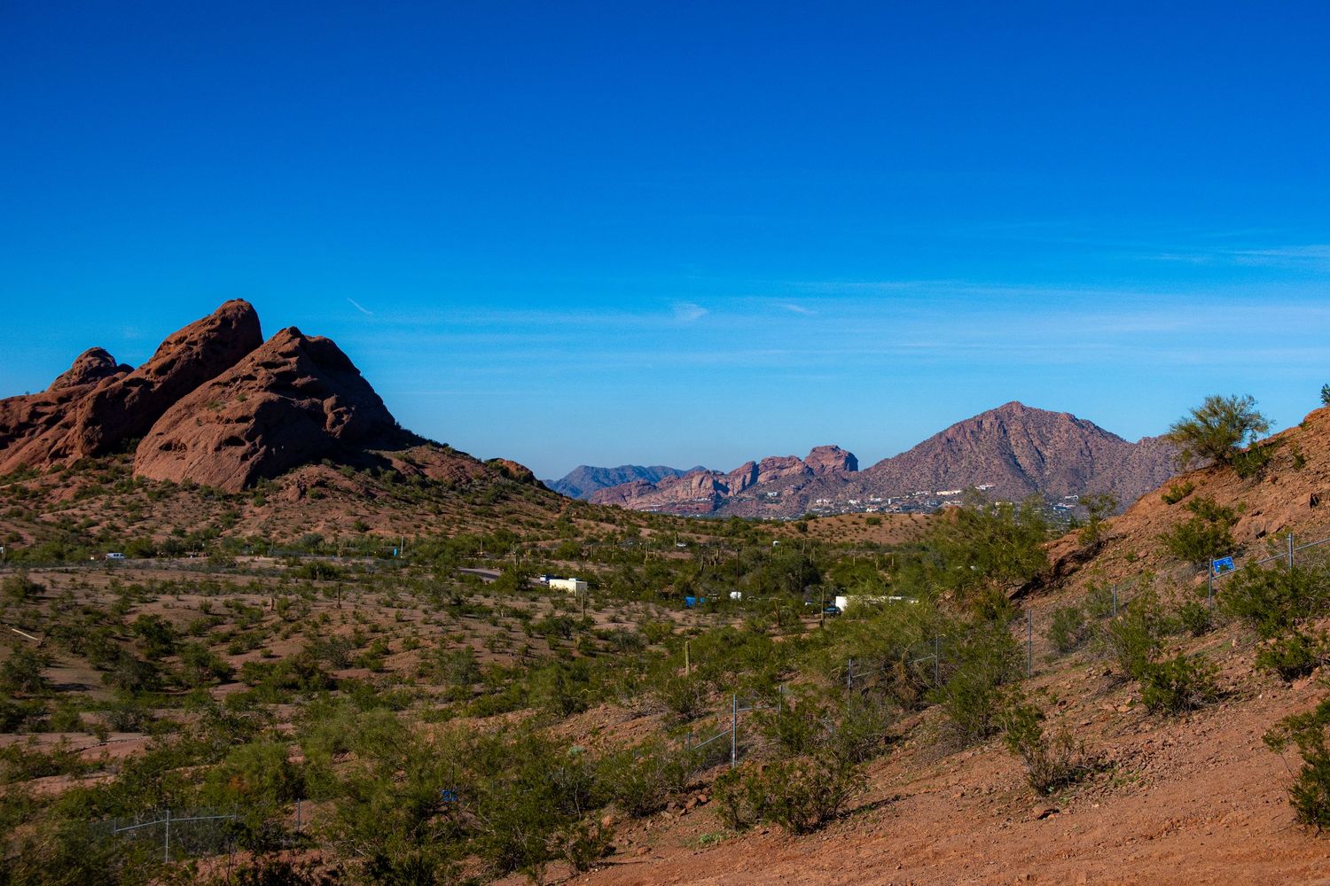 Desert landscape with red rock formations and mountains under clear blue skies in Arizona.