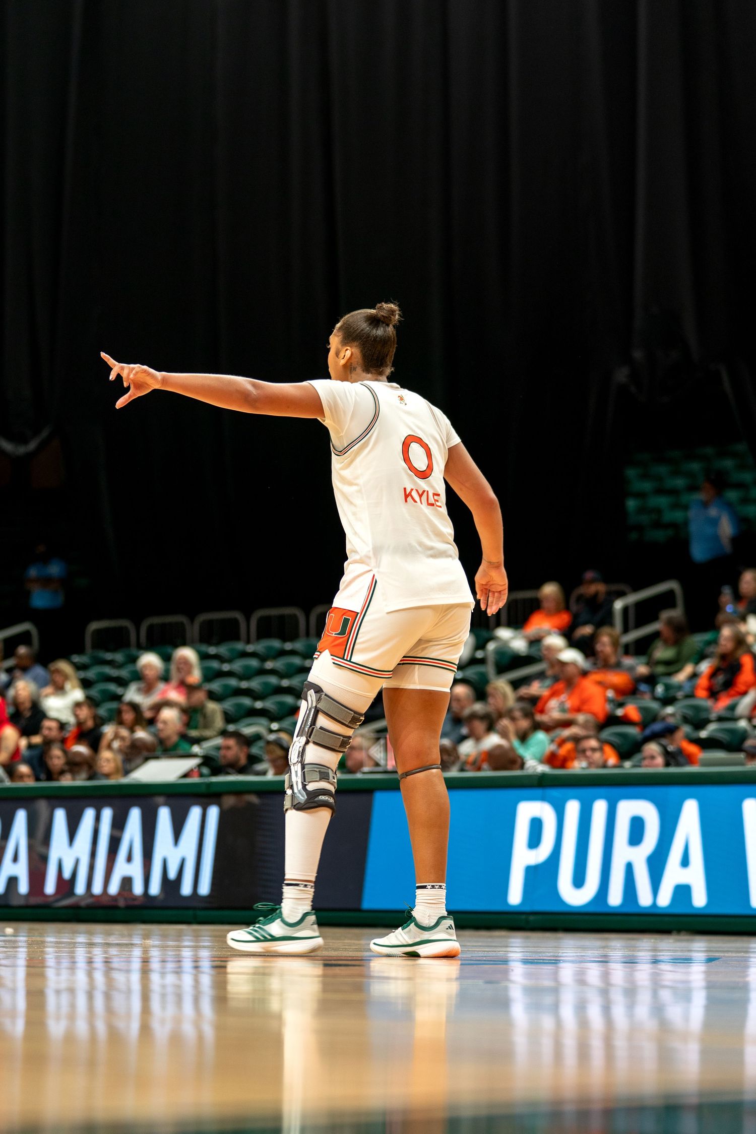 Players in white uniforms stretch on a basketball court with advertising boards visible.