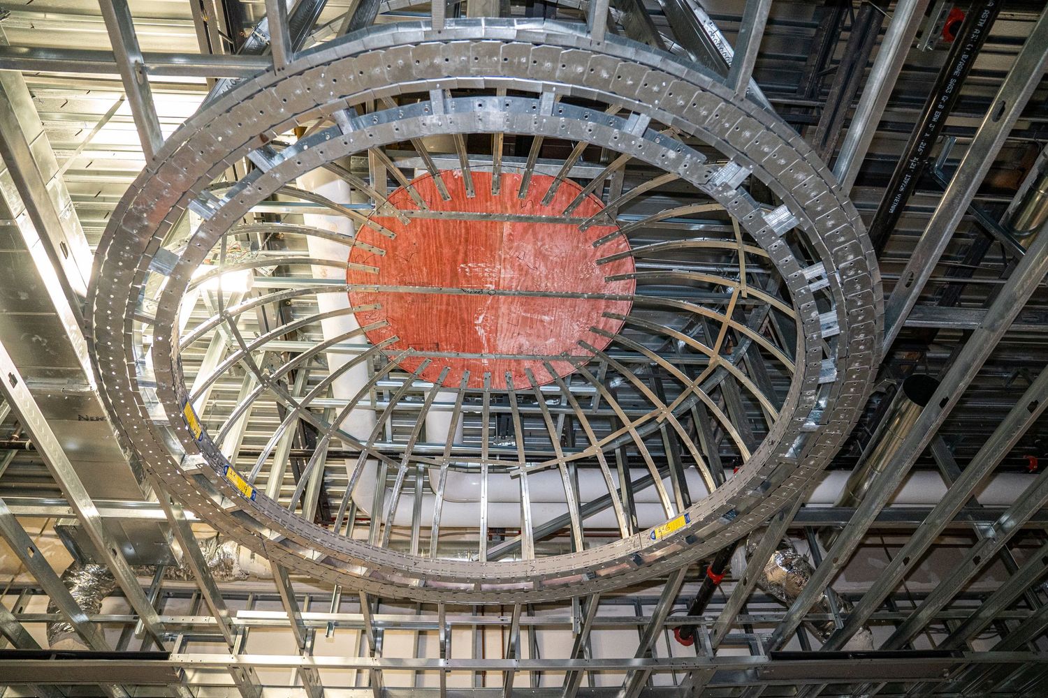 Circular architectural ceiling detail with metal framework and orange accent lighting.