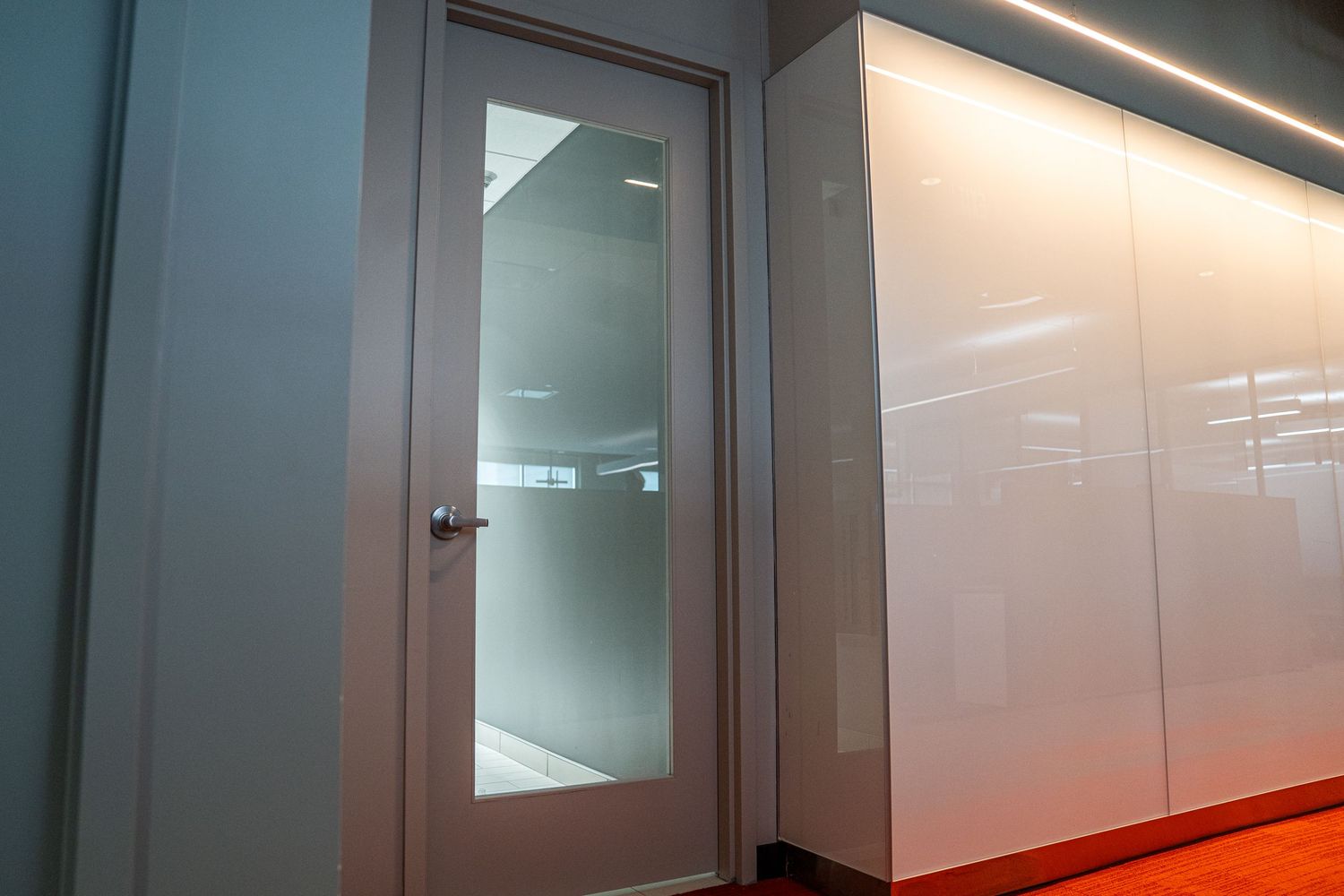 Modern glass door installation in commercial space with white wall panels.