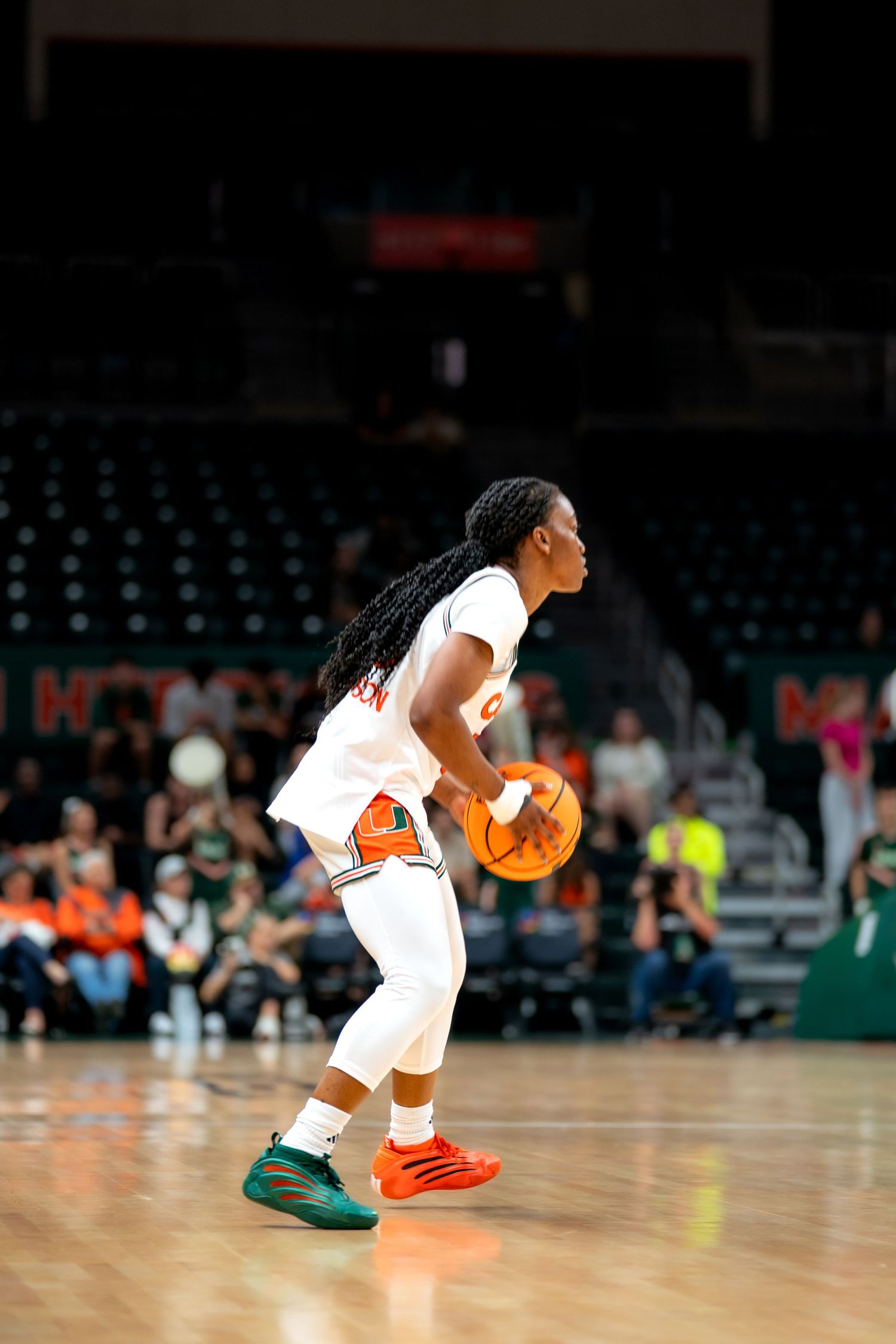 Basketball player in white uniform dribbling low to the court during intense game action.