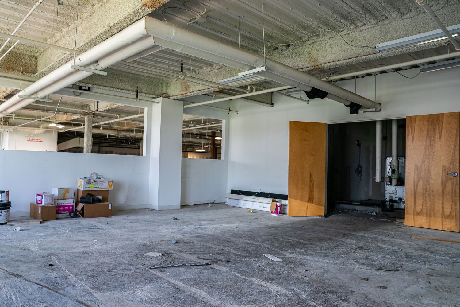 Raw commercial space under construction showing concrete floors and exposed ceiling.