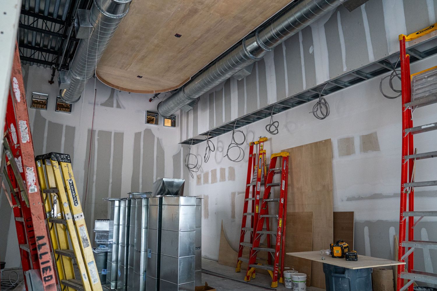 Construction area with drywall partitions and red ladders visible along corridor.
