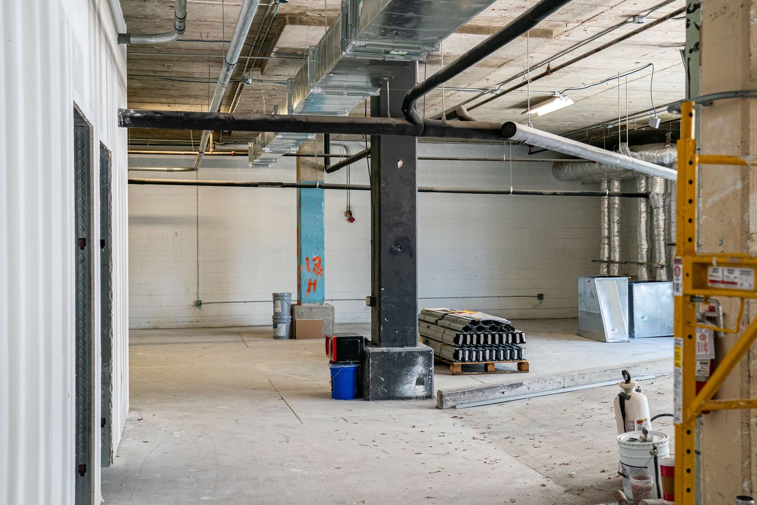 Unfinished commercial space showing exposed ductwork and utilities during renovation.