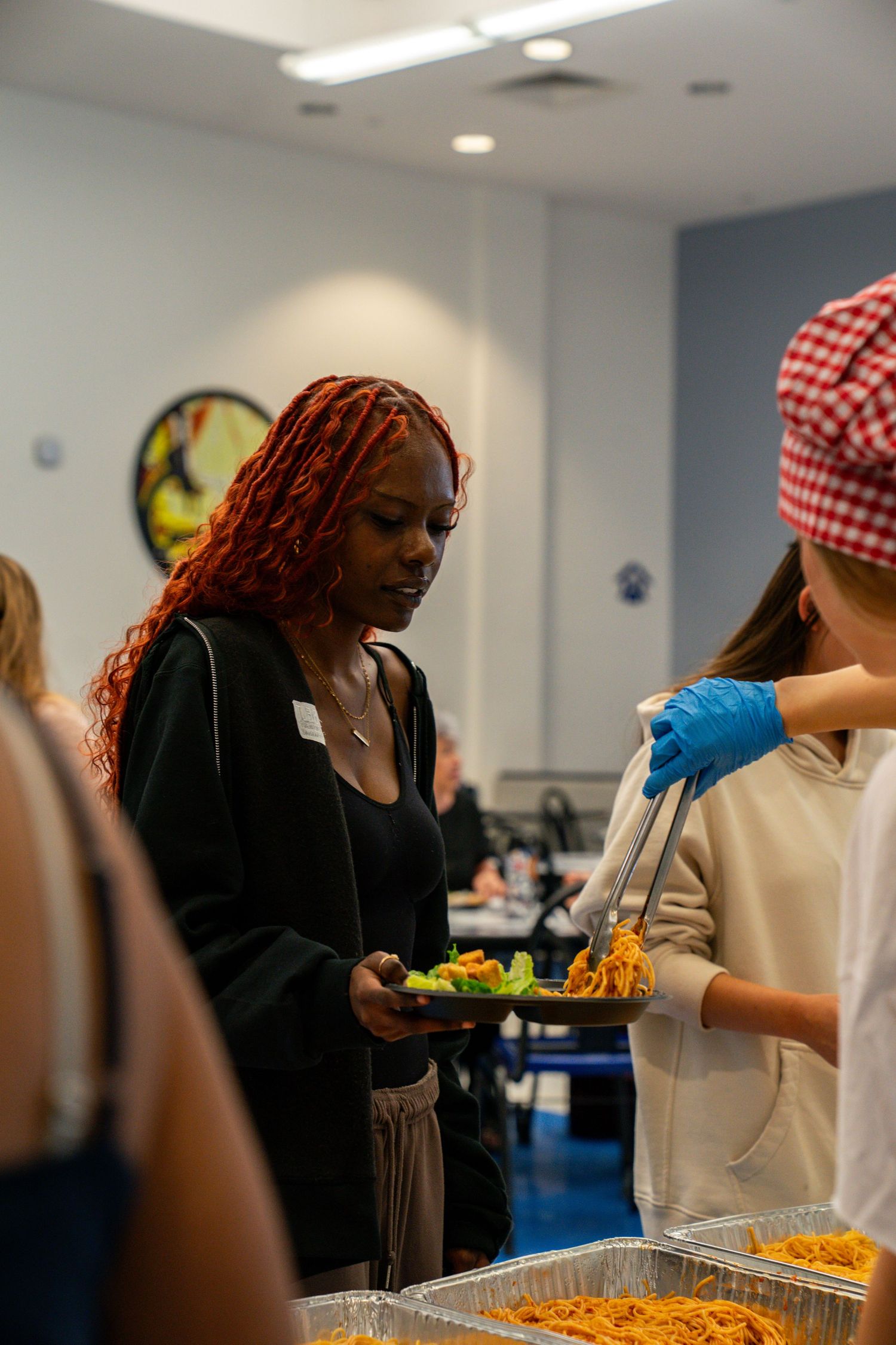 Food service workers in protective gear serving from buffet trays.