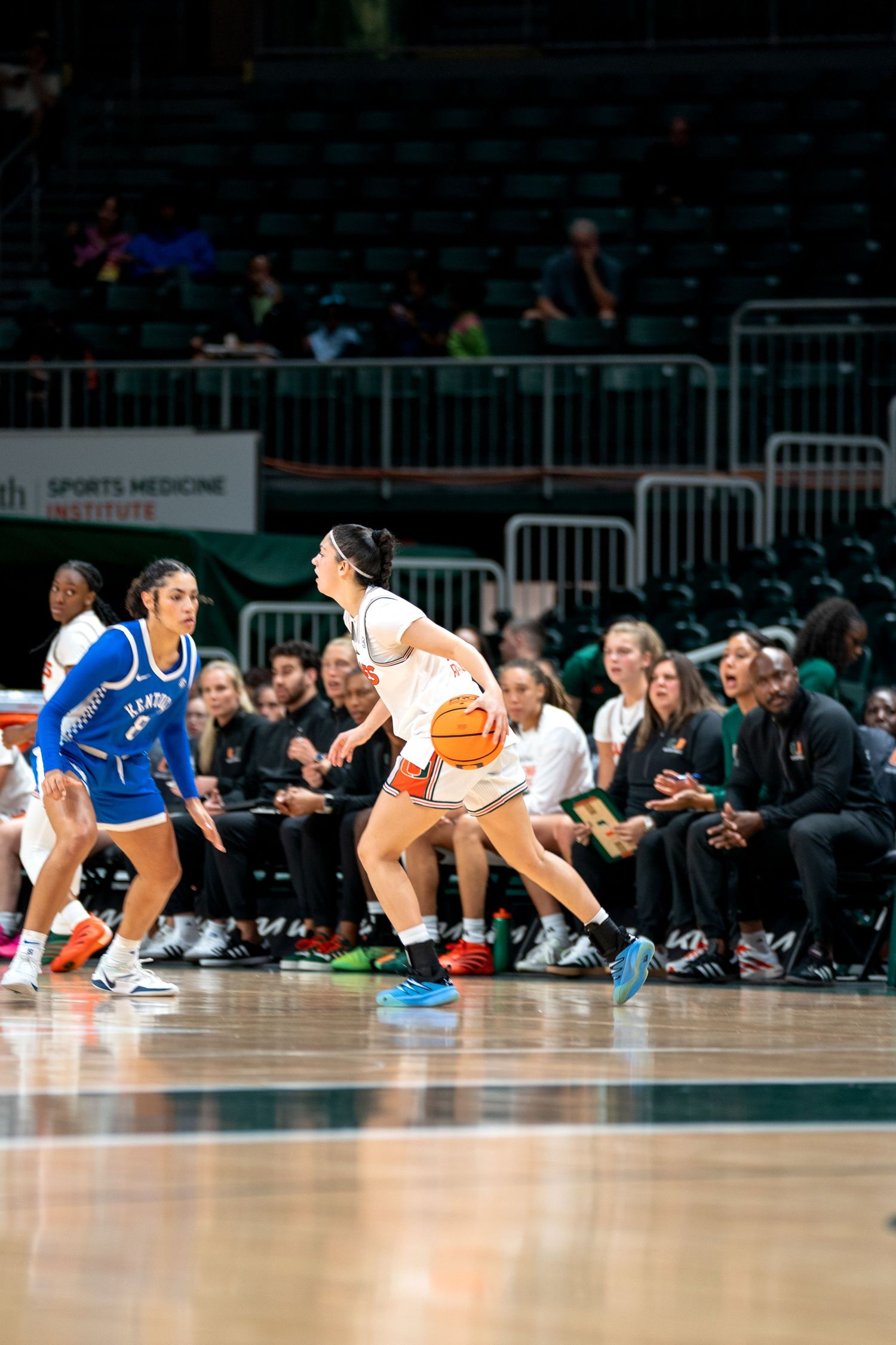 Basketball players diving for a loose ball during an intense game at the University of Miami.