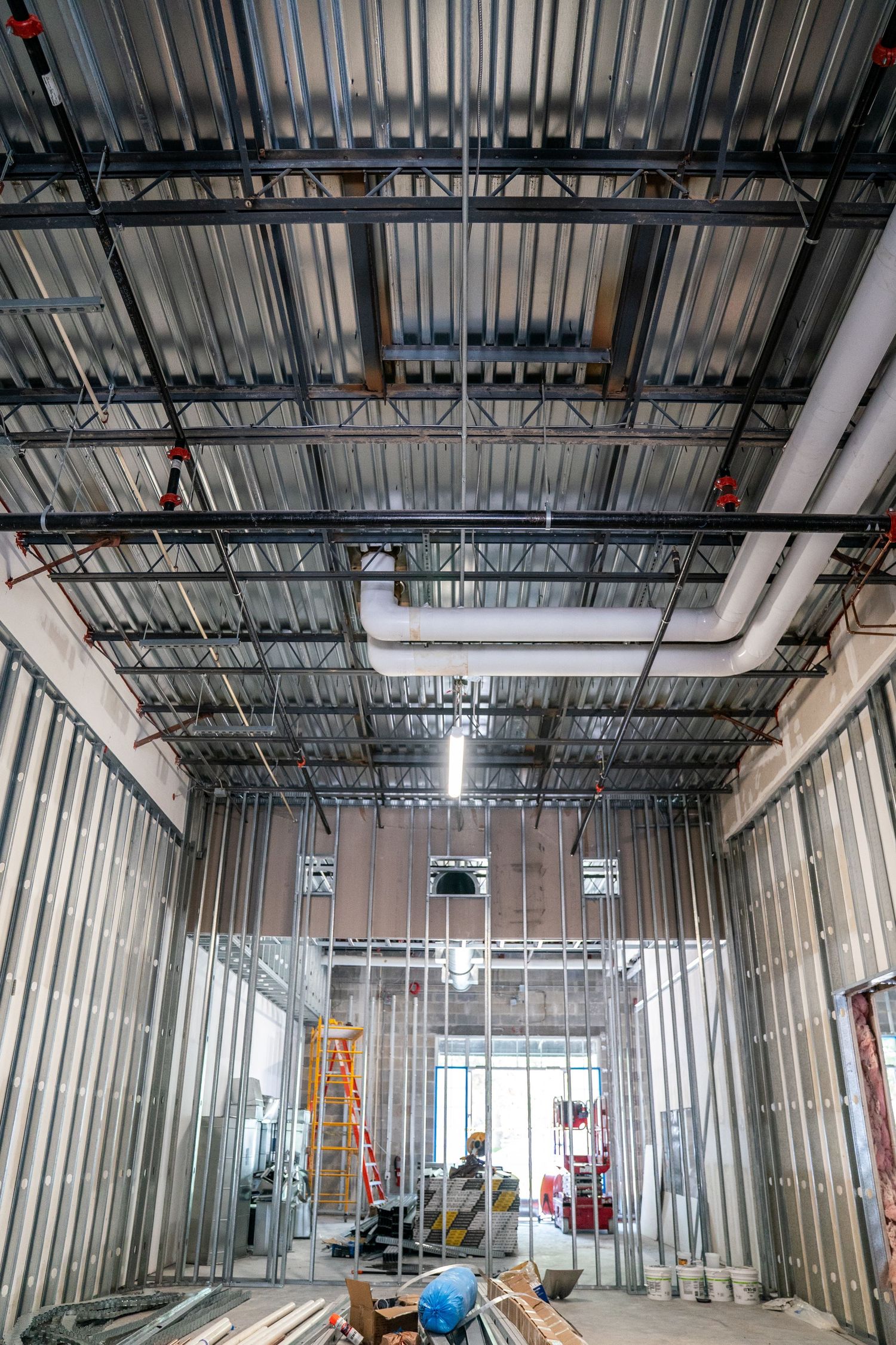 Large commercial space renovation with exposed ceiling systems and metal stud framing.