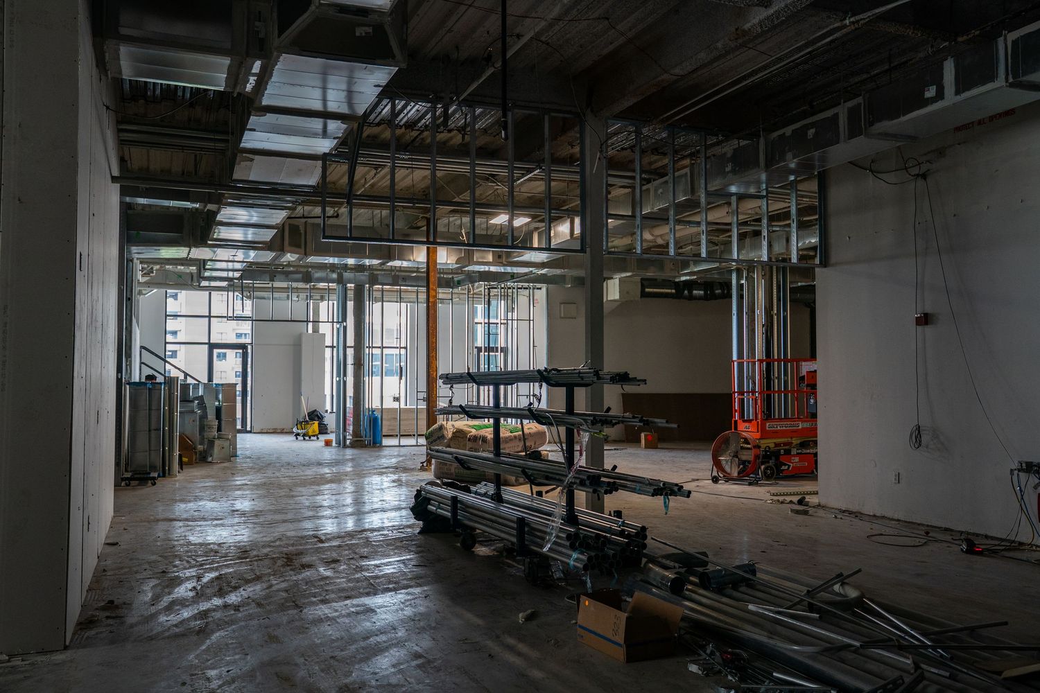 A large industrial space under renovation with construction equipment and exposed ceiling utilities.