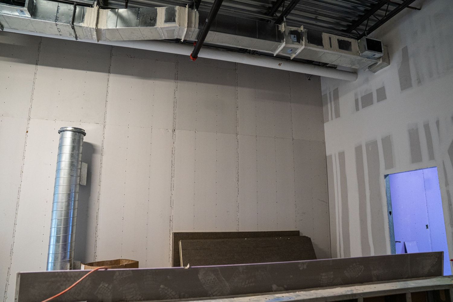 Commercial space under construction showing metal ductwork and exposed ceiling infrastructure.