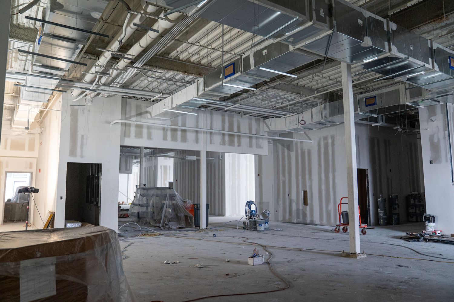 Long view of commercial renovation showing exposed ceiling infrastructure and white walls.